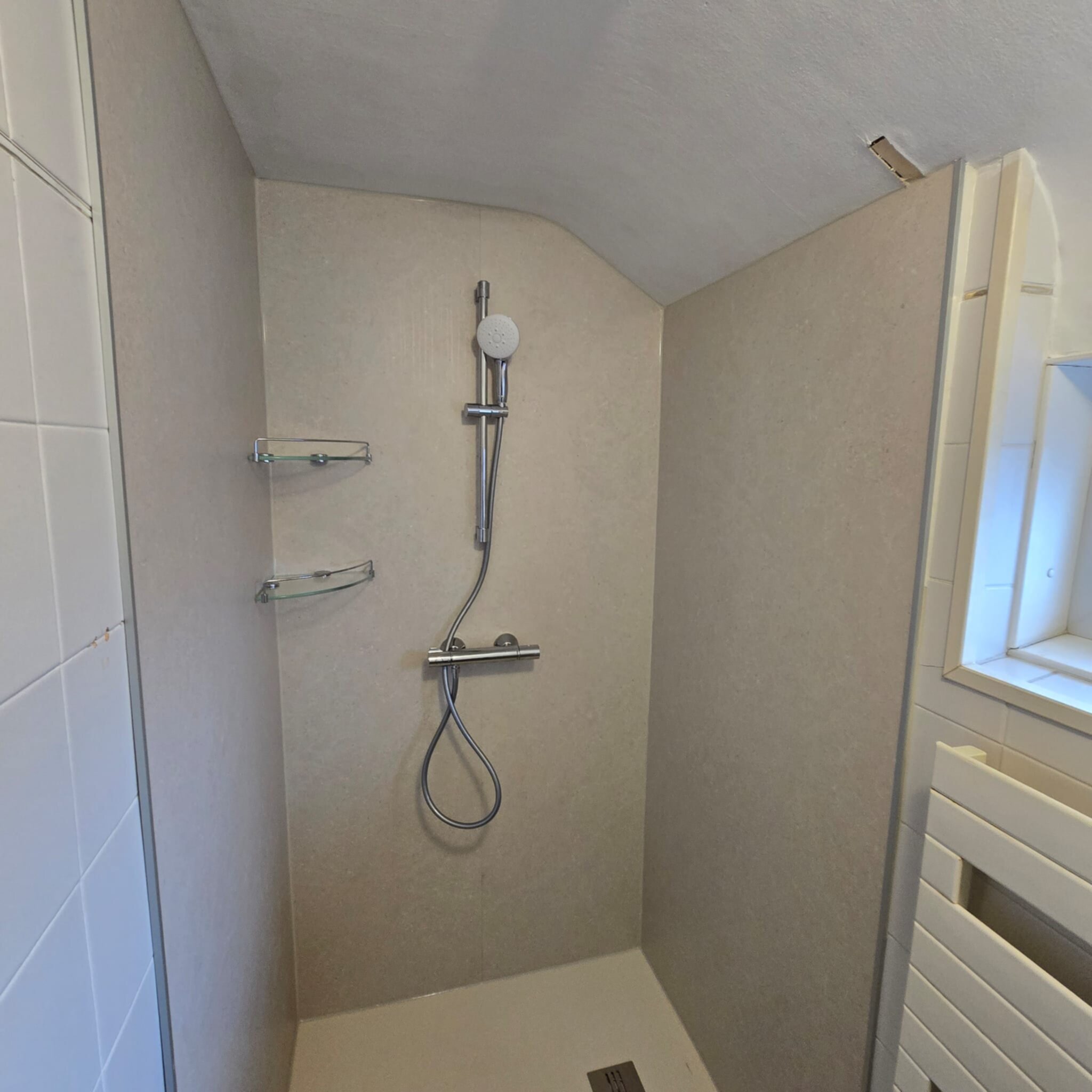 Douchecellen met beige en witte betegeling en chroom douchekraan