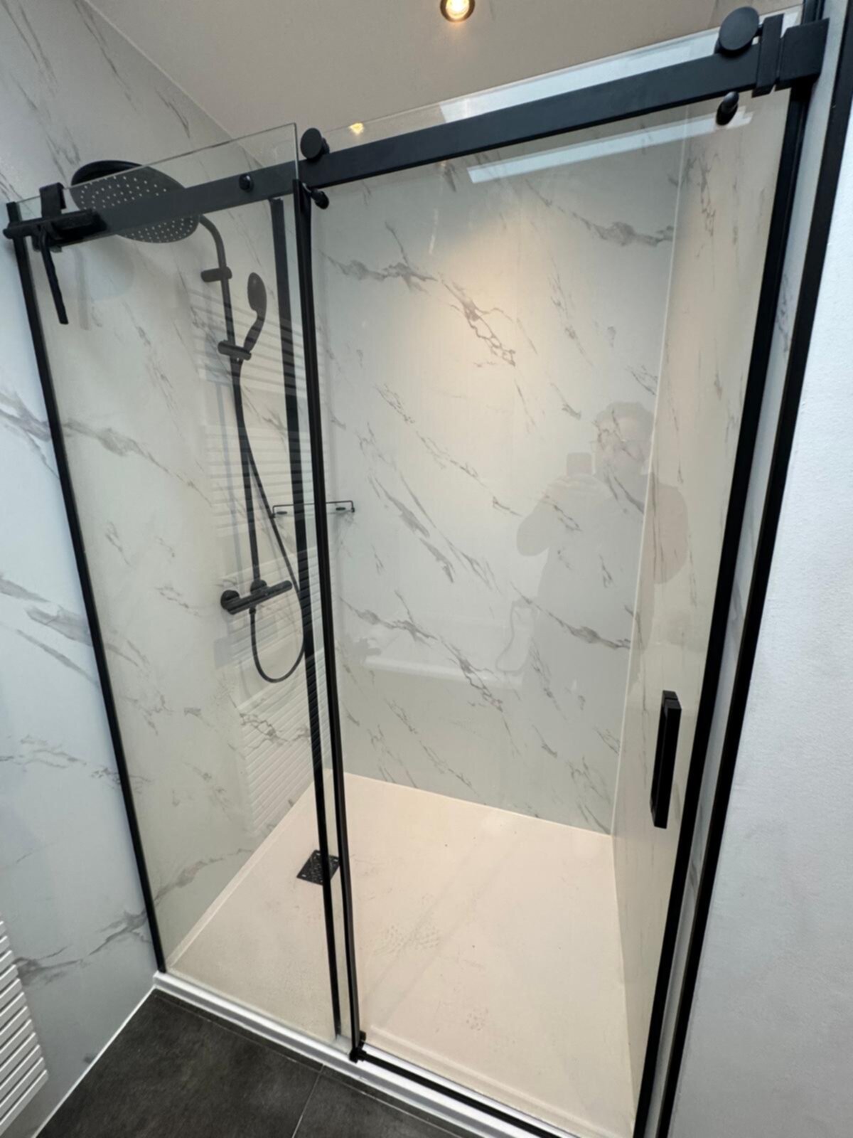 Douchecabine met glazen deur en zwarte metalen frame in moderne badkamer
