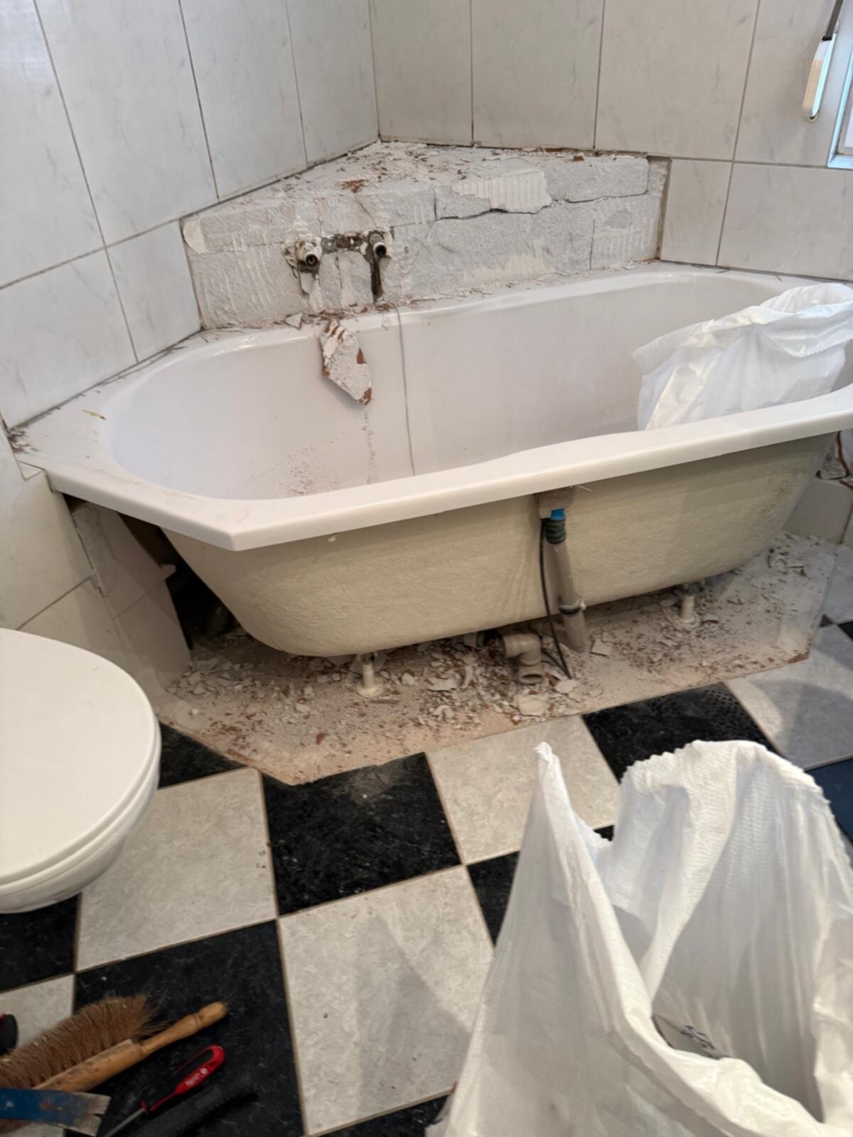 Slechte staat badkamer met oude badkuip en kapotte tegels