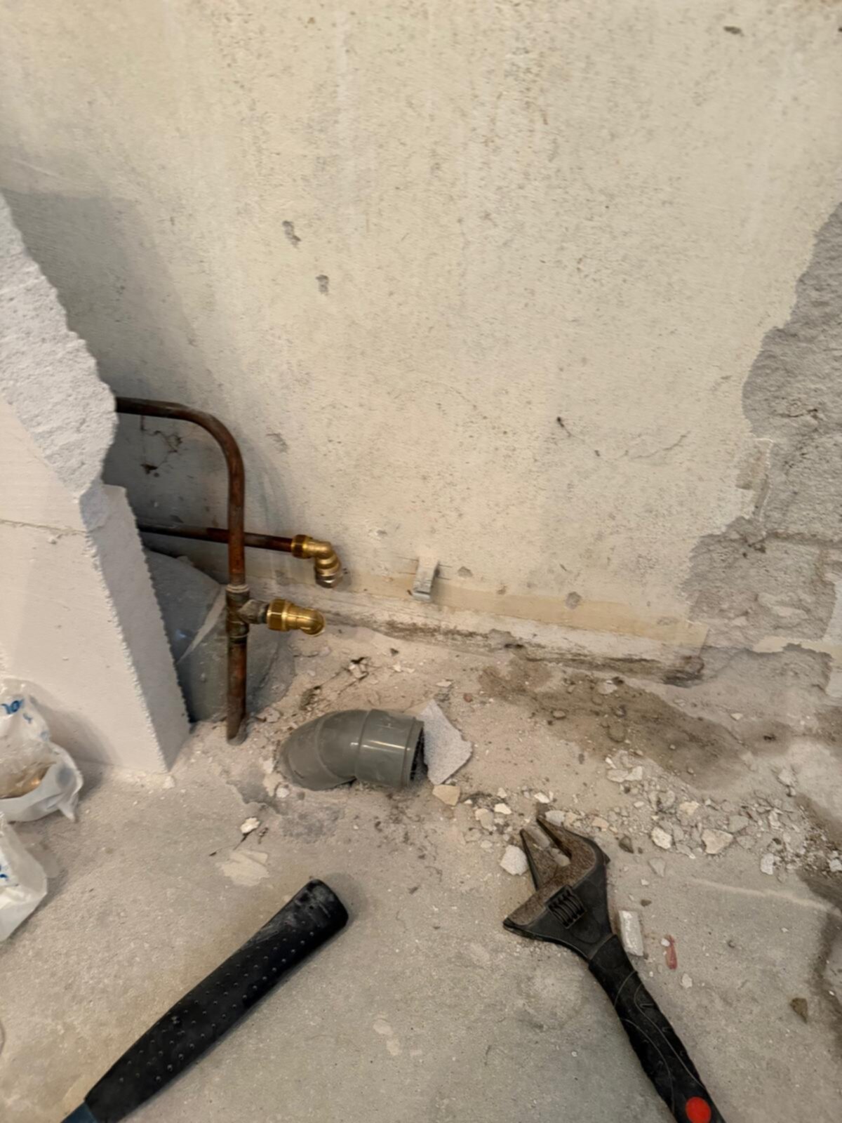 Sleuf in badkamer vloer met koperen waterleidingen en gereedschap