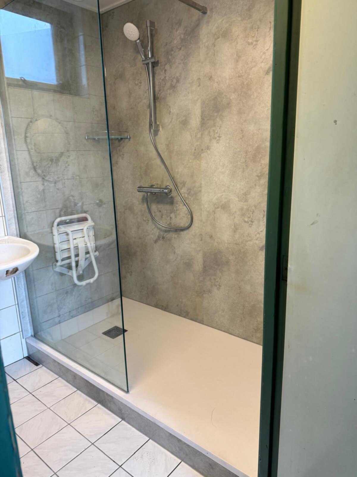 Douchecabine met glazen wand, betegelde muren en witte douchebak