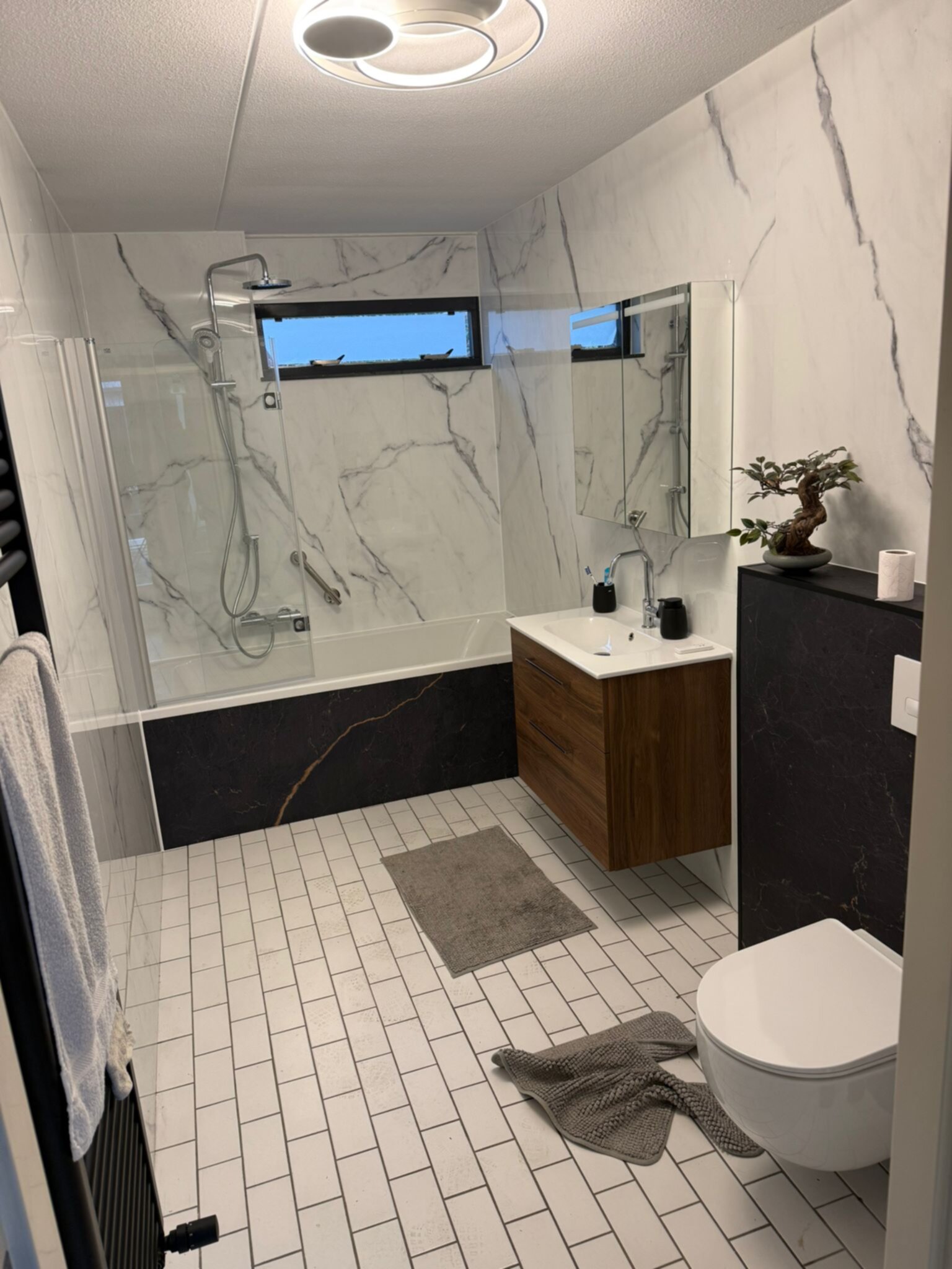 Moderne badkamer met marmerlook tegels, houten meubels en witte sanitair