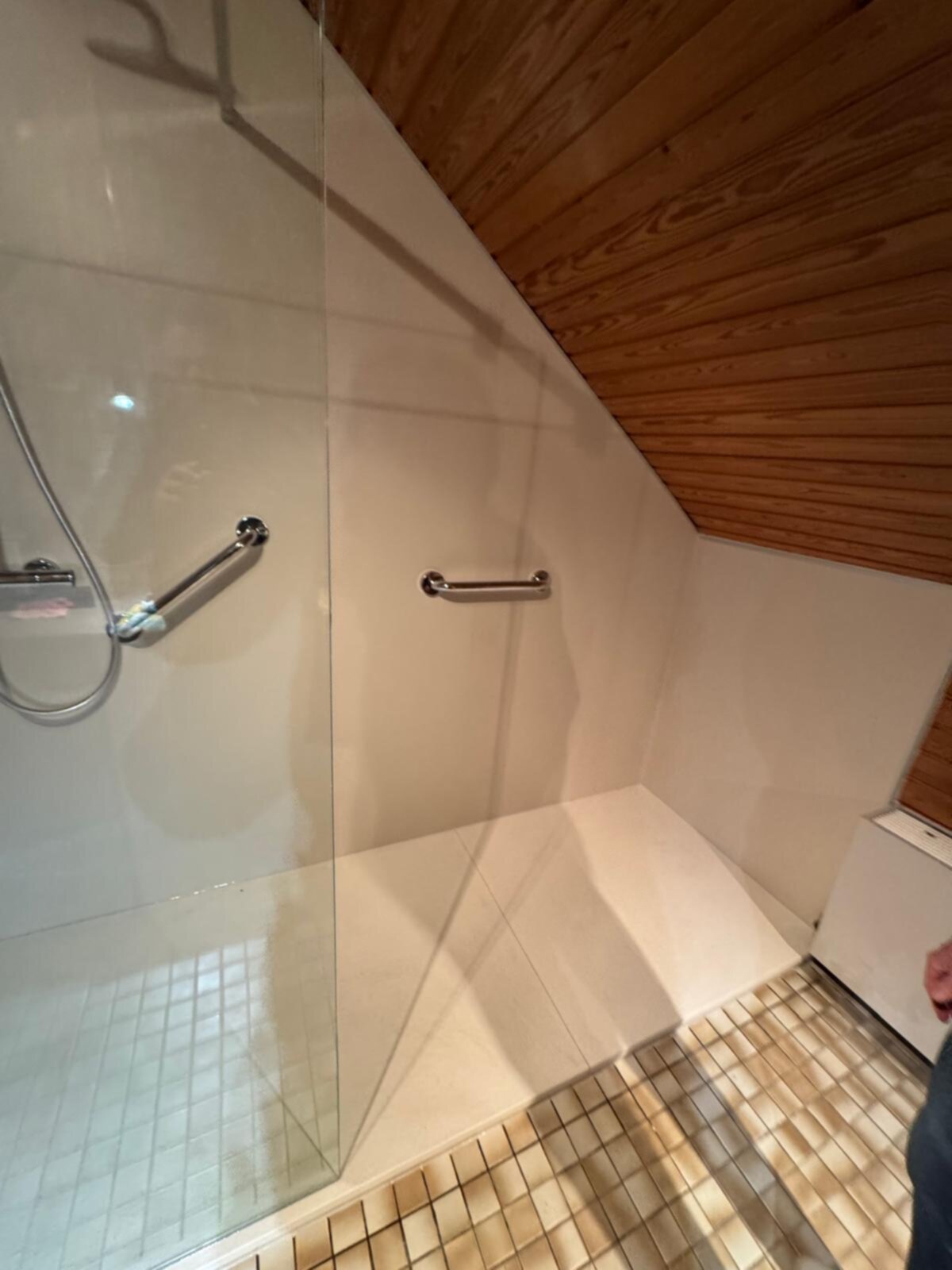 Douchecabine met glazen wand en deur, witte betegeling en houten plafond