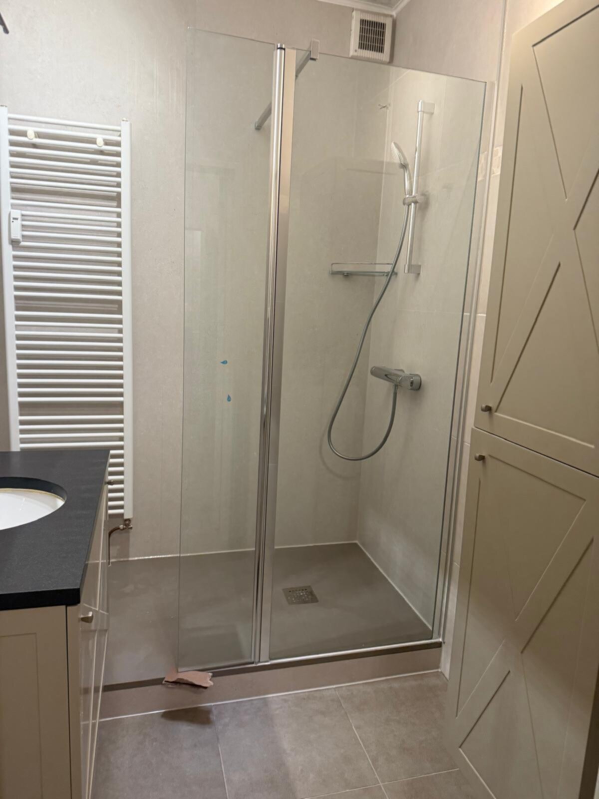 Douchecabine met glazen deur en zilveren hardware in moderne badkamer
