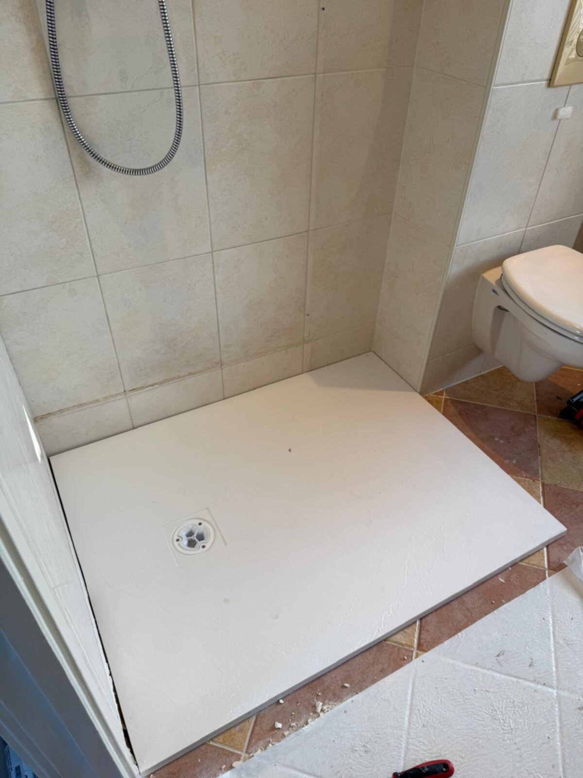 Douchevloer in aanbouw met betegelde muren en wit toilet