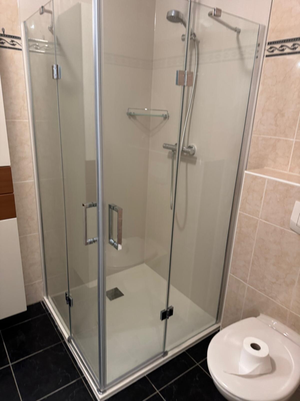 Douchecabine met glazen deur en toilet in moderne badkamer
