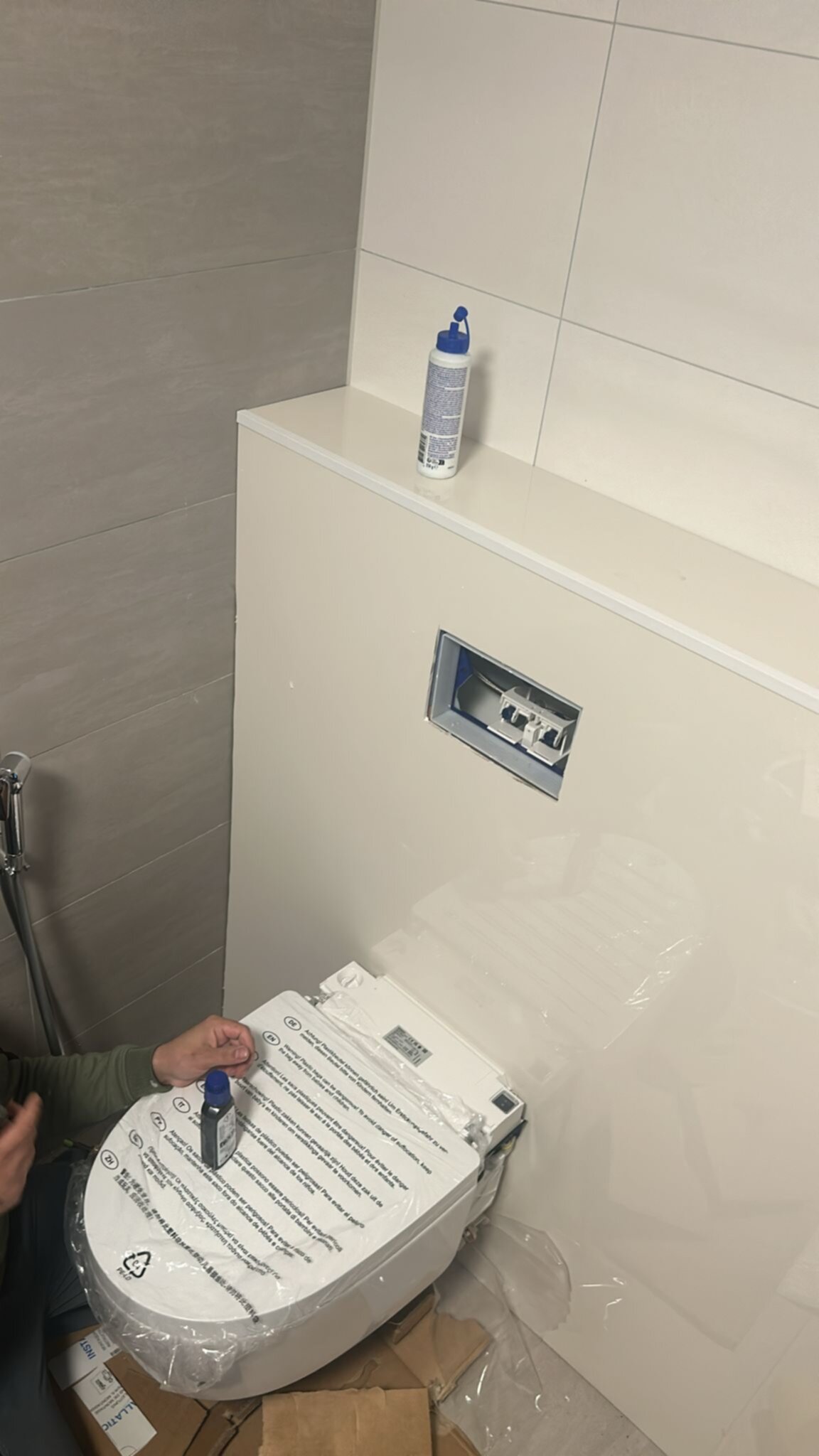 Wit toilet in aanbouw, beige betegeling en verpakte toebehoren