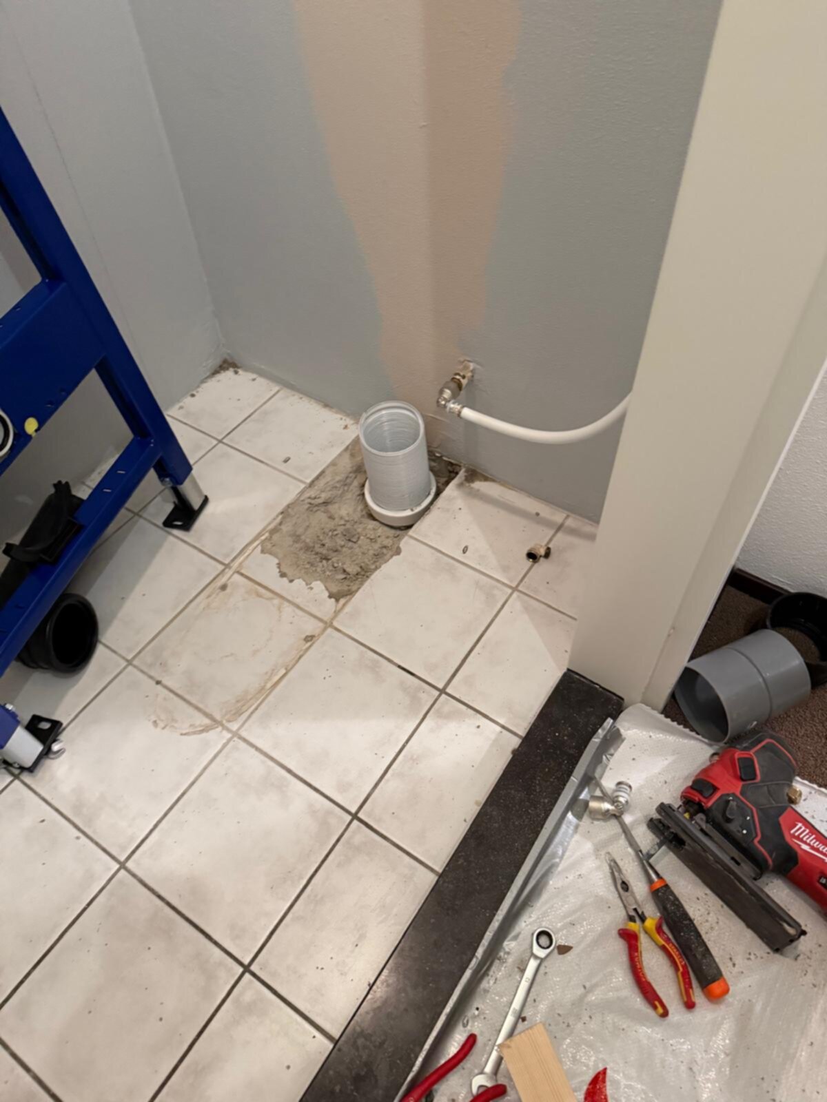 Sfeerbeeld van een badkamer tijdens renovatie met gereedschap en opengelegd leidingwerk