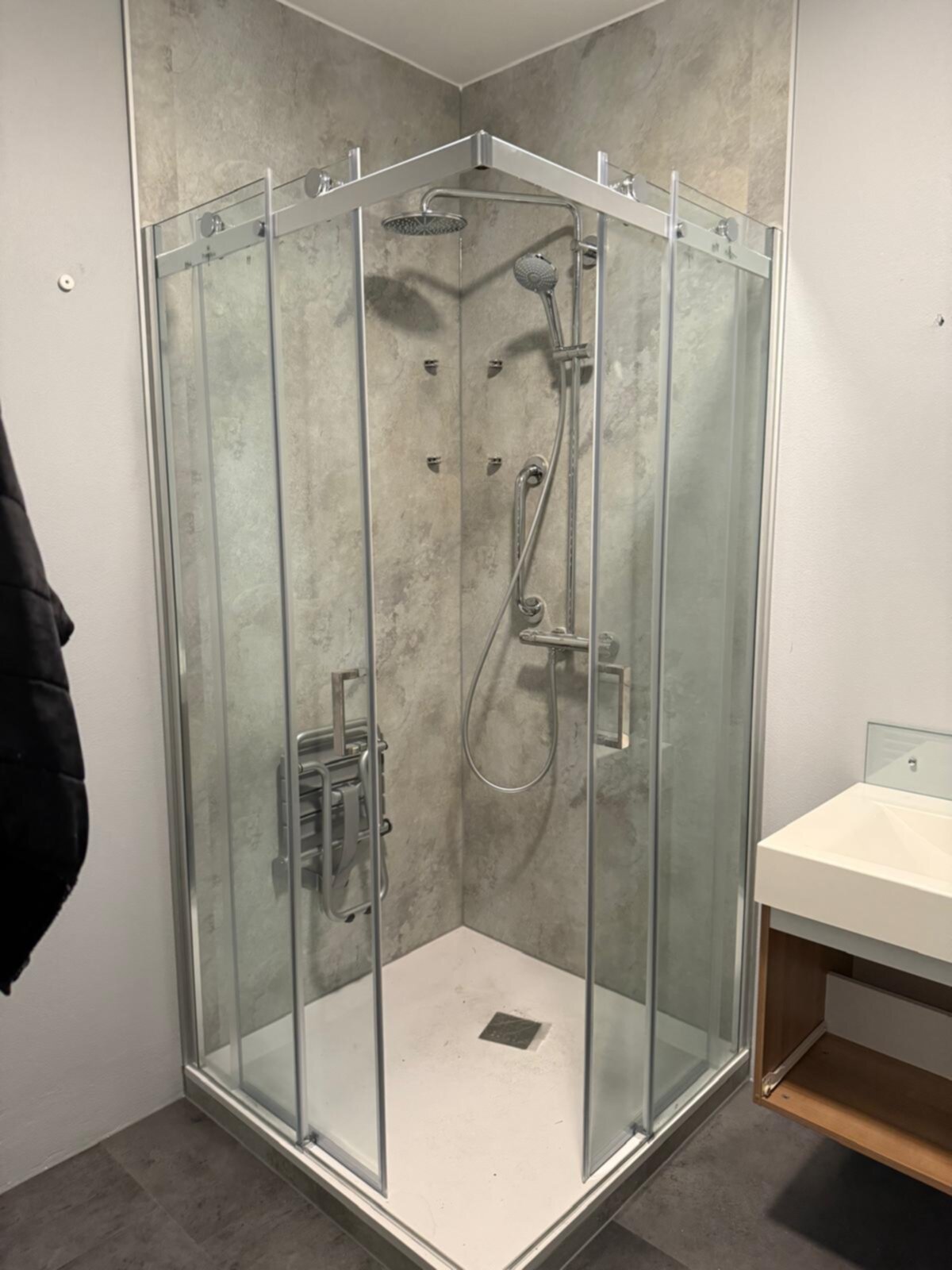 Douchecabine met glazen wanden en een betegelde achterwand in een moderne badkamer