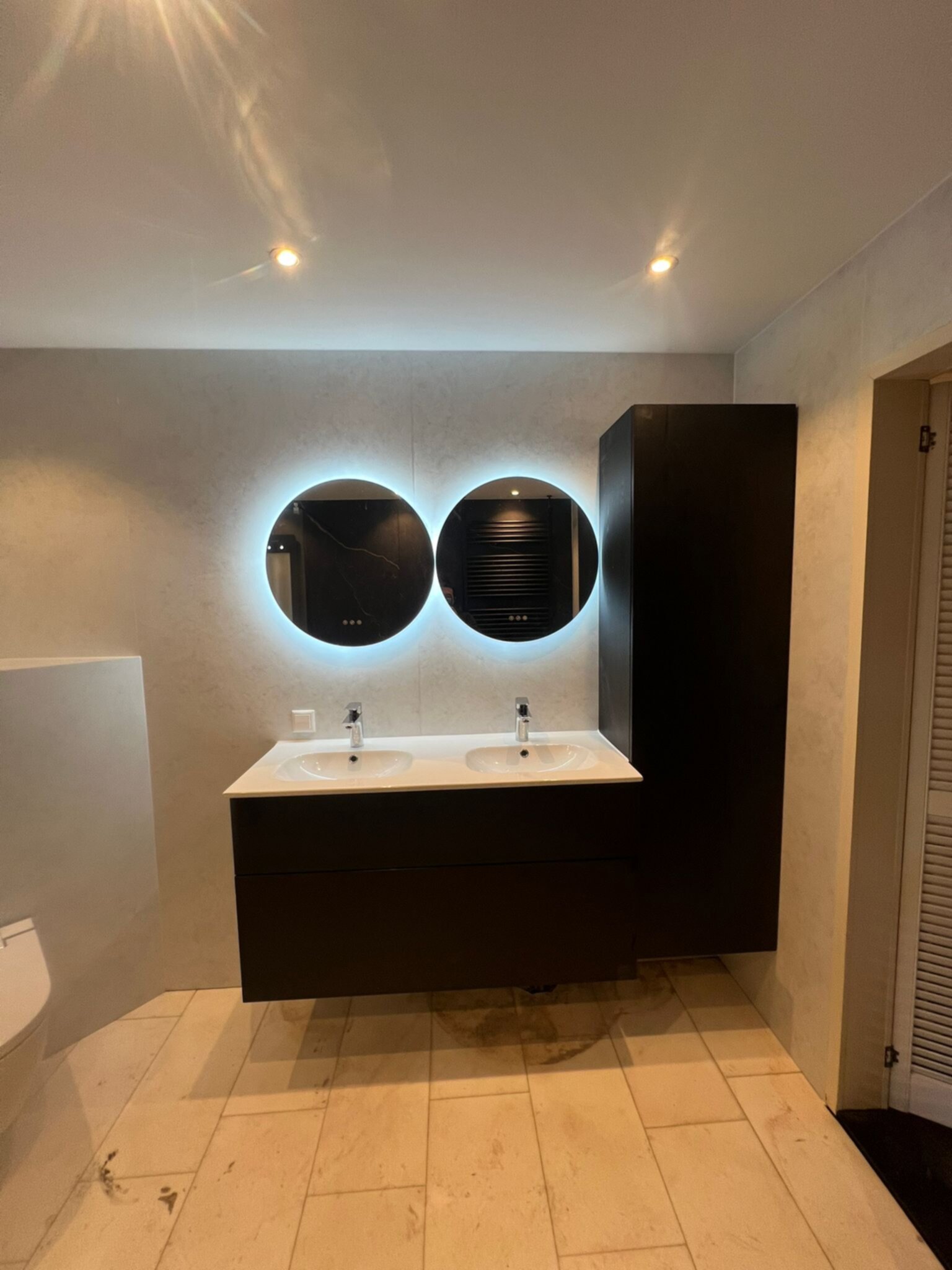 Moderne badkamer met dubbele wastafel en verlichte ronde spiegels