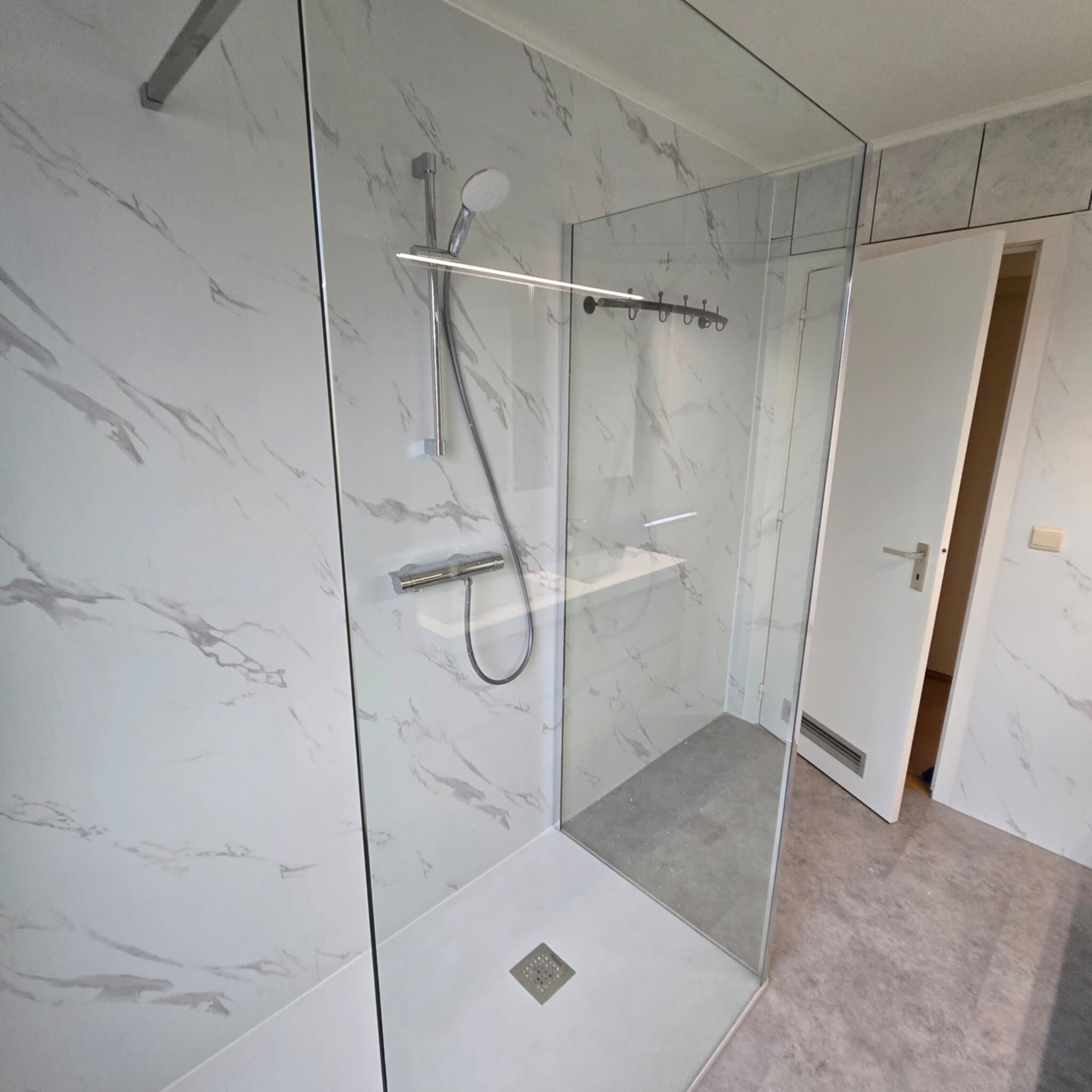Douchecabine met glazen wand en marmerlook tegels in grijs en wit