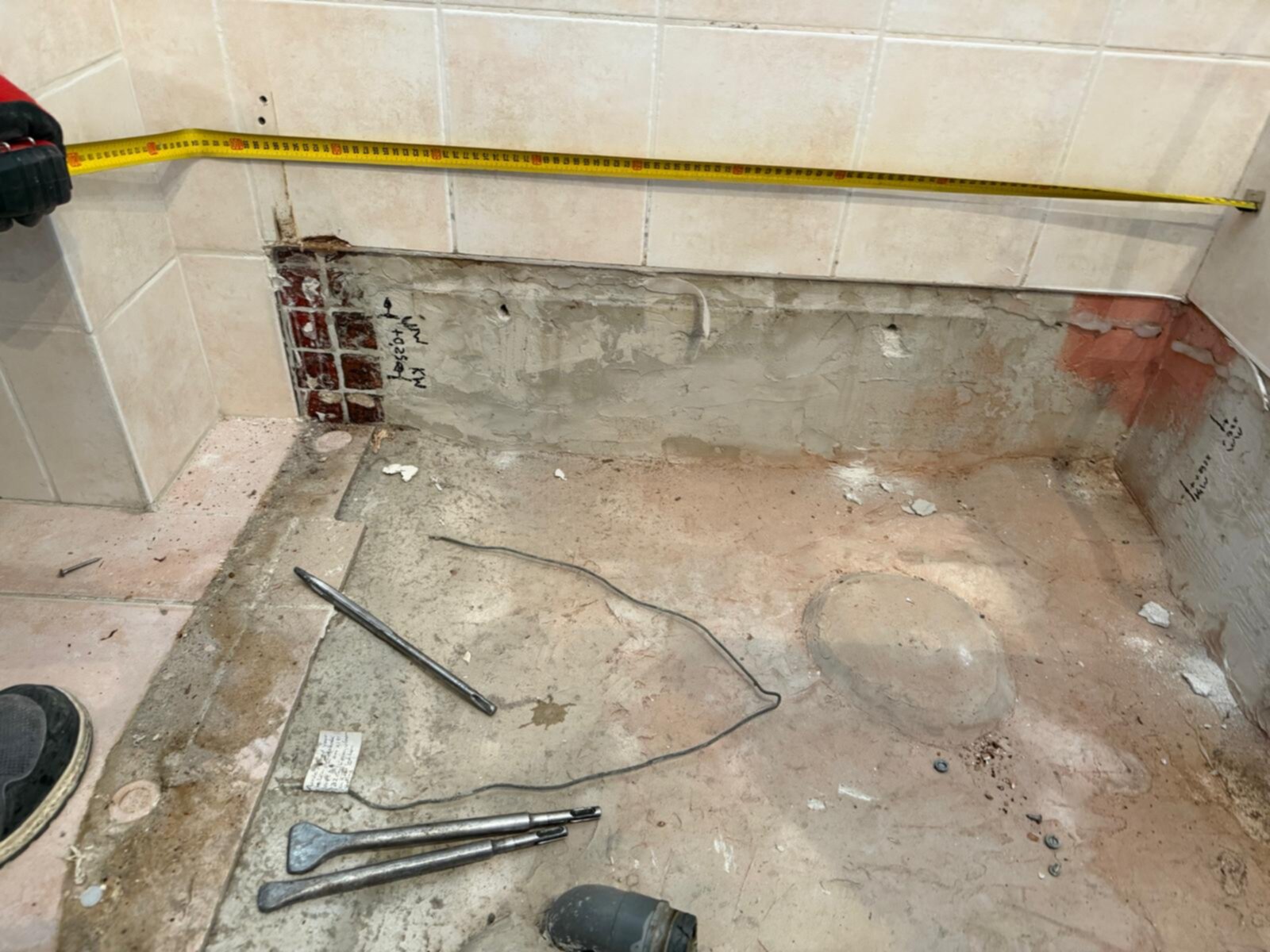 Slecht onderhouden badkamer in renovatie, met gereedschap en meetlint