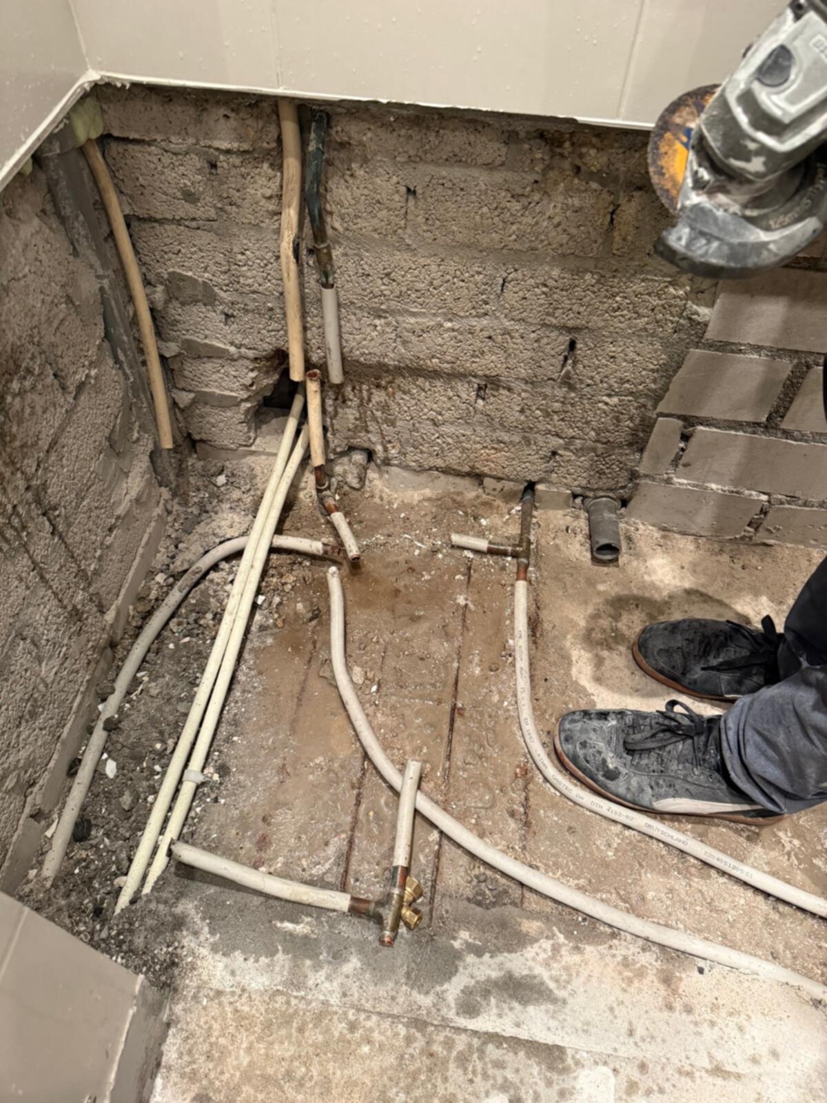 Sleuf in badkamer met blootgelegde leidingen en rioleringsbuizen tijdens renovatie