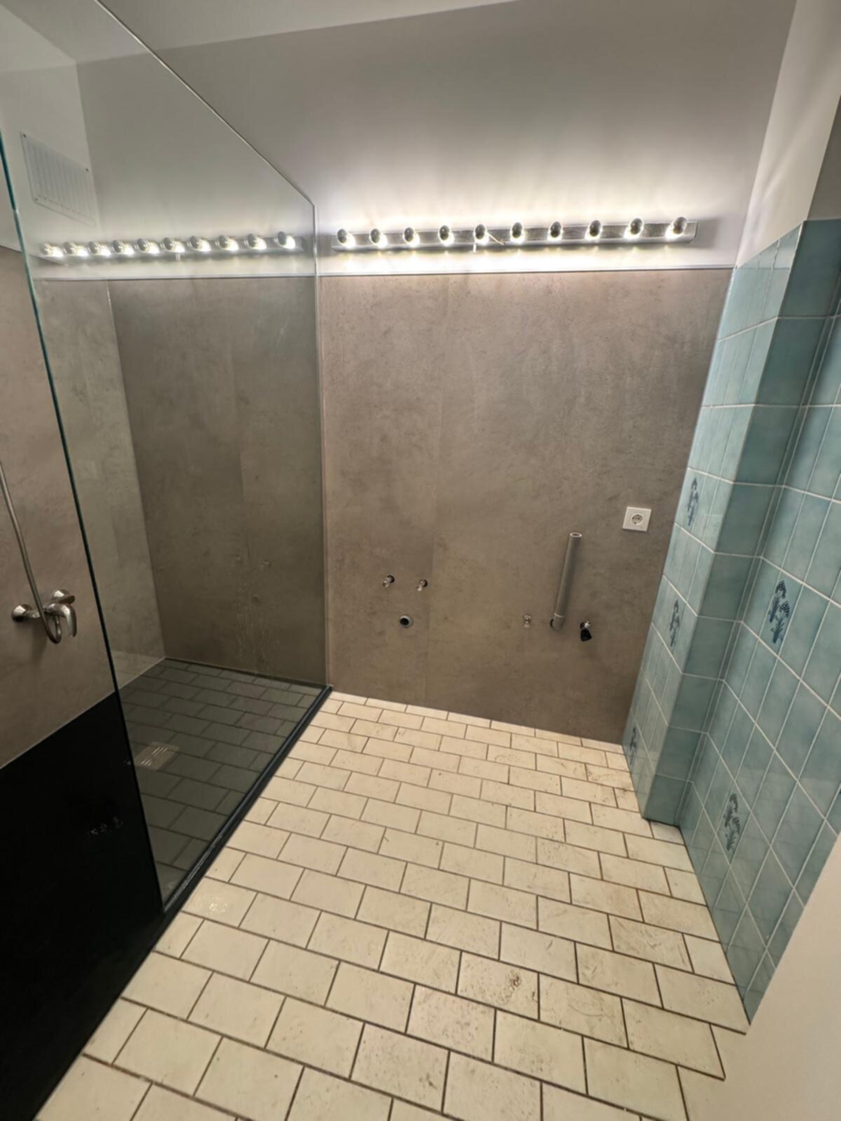 Douche ruimte met grijze wanden, witte vloer en blauwe betegeling