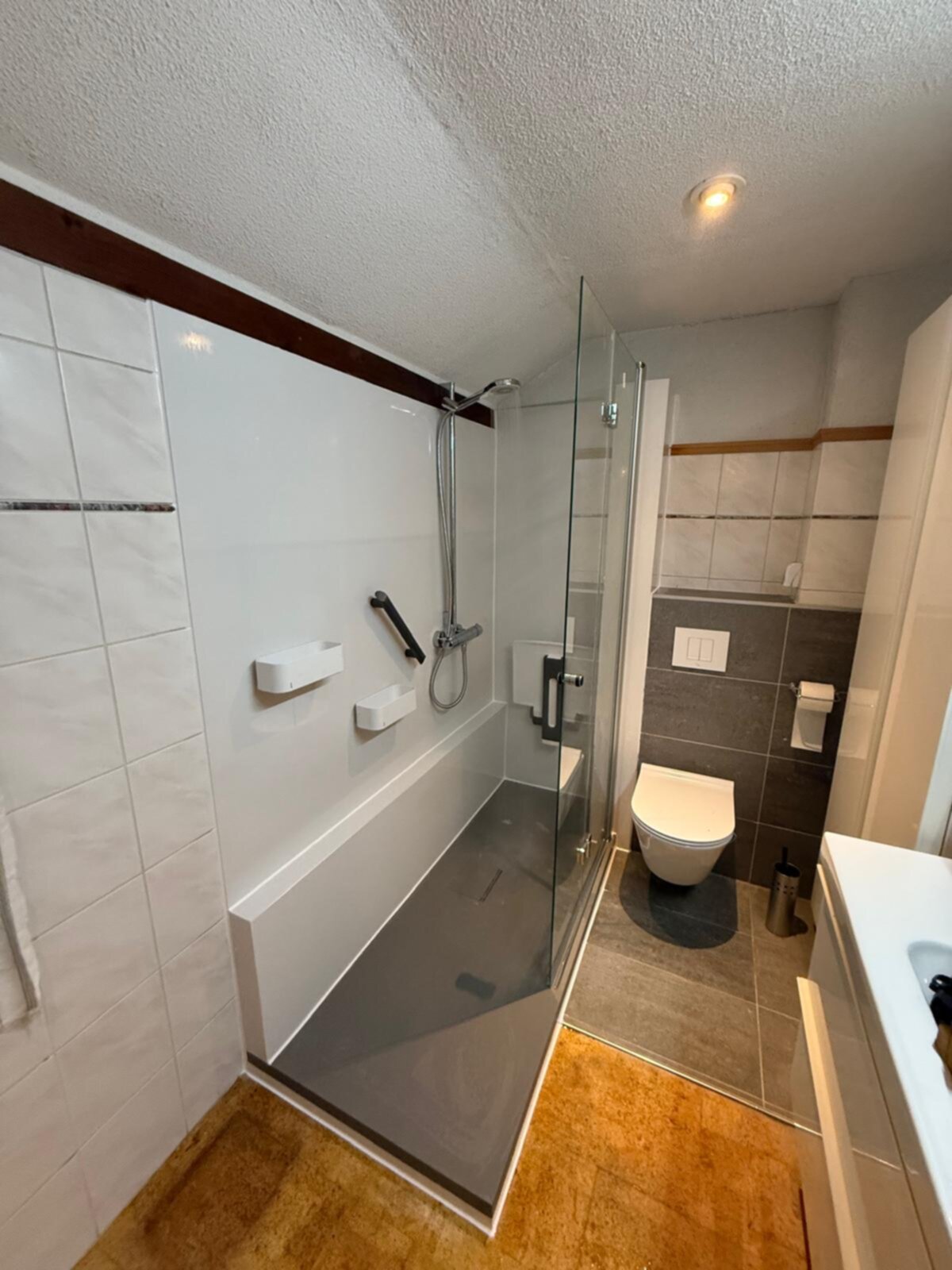 Badkamer met witte en grijze tegels, glazen douchecabine en moderne sanitaire voorzieningen
