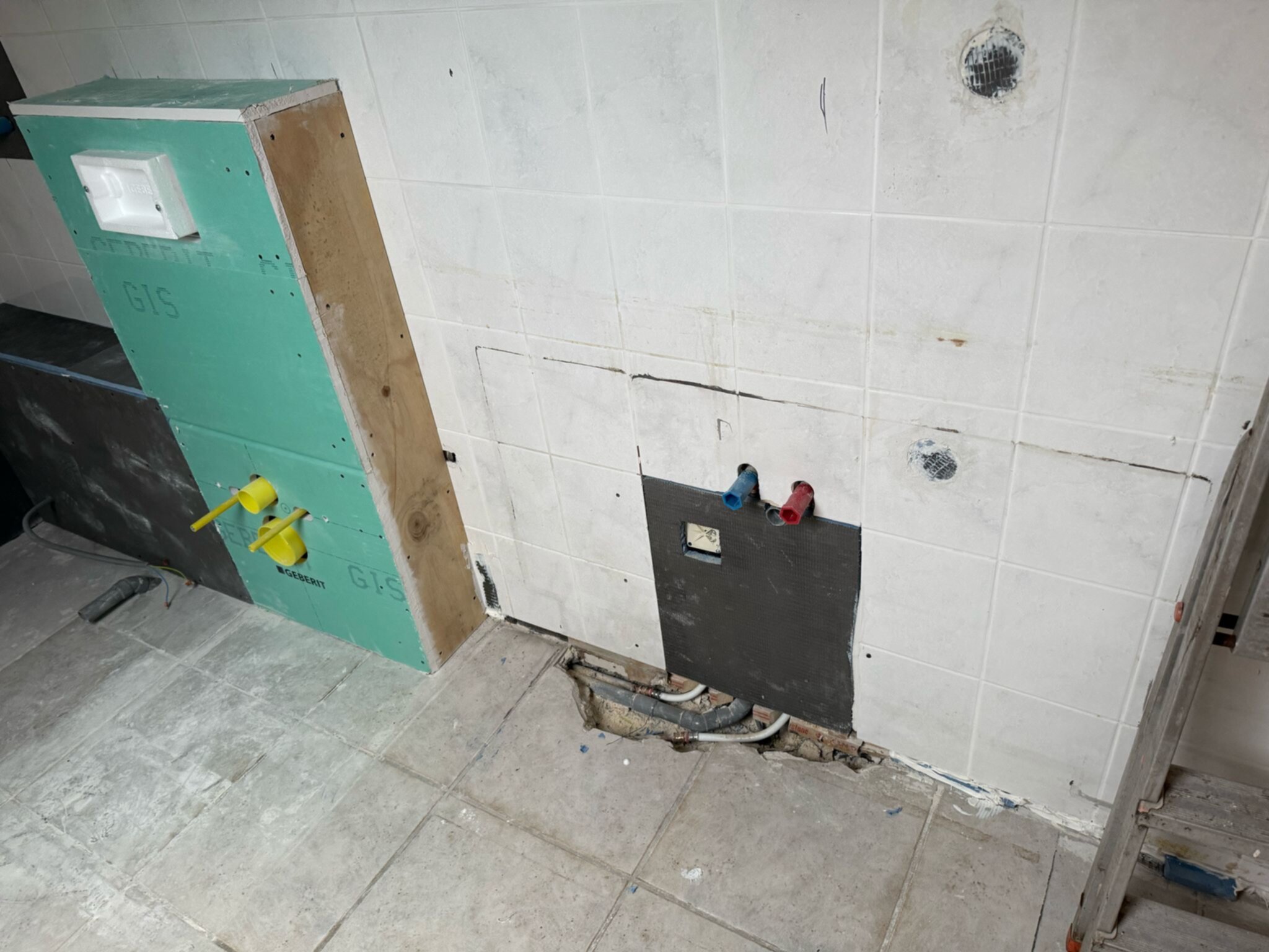 Badkamer renovatie in uitvoering met blootgelegde leidingen en tegelwerk