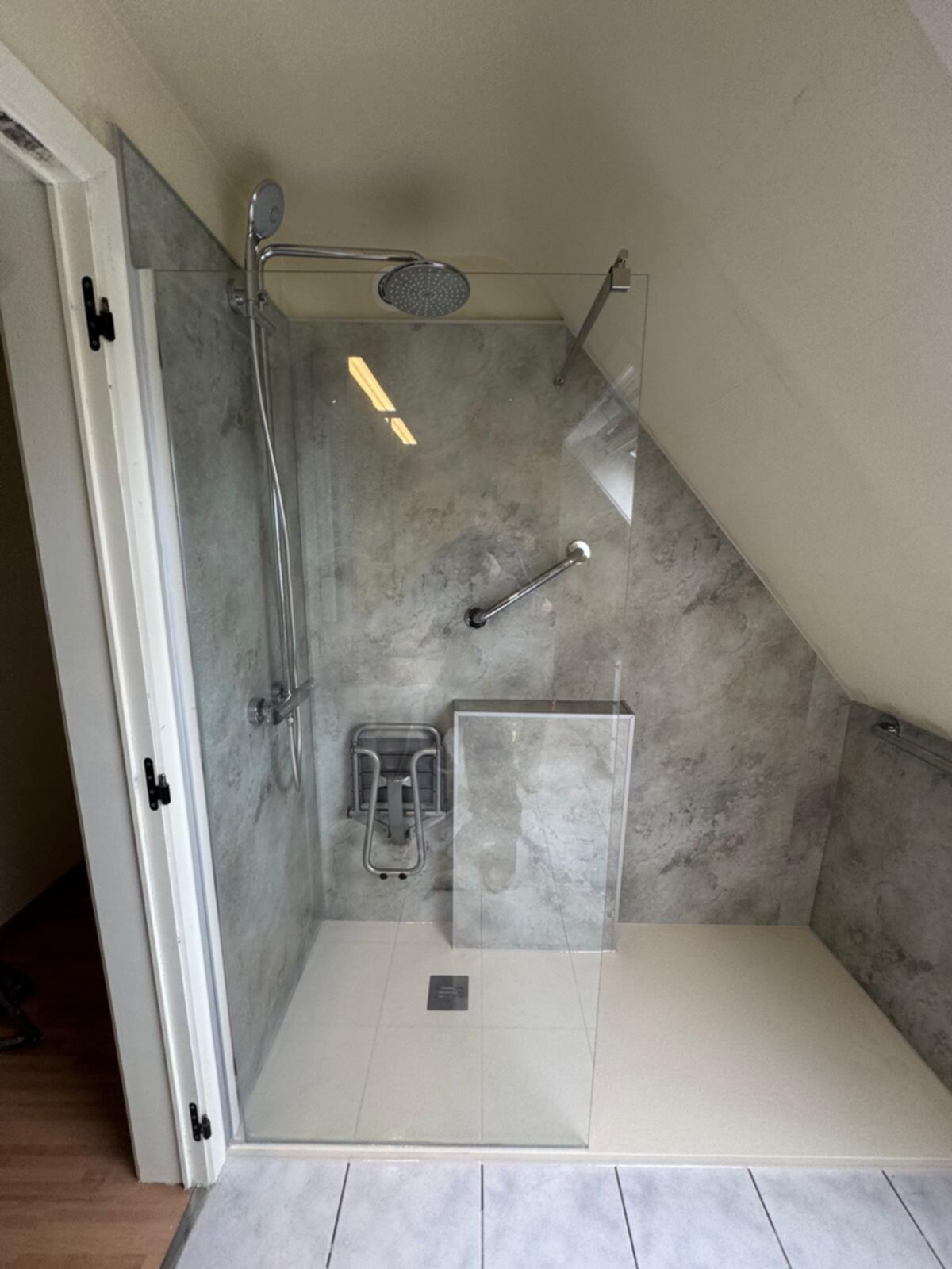 Douche met glazen deur en betegelde wanden in grijze marmerlook