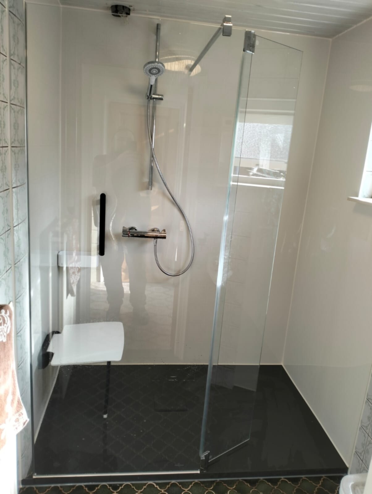 Douchecabine met glazen wand, witte tegels en zwarte vloer