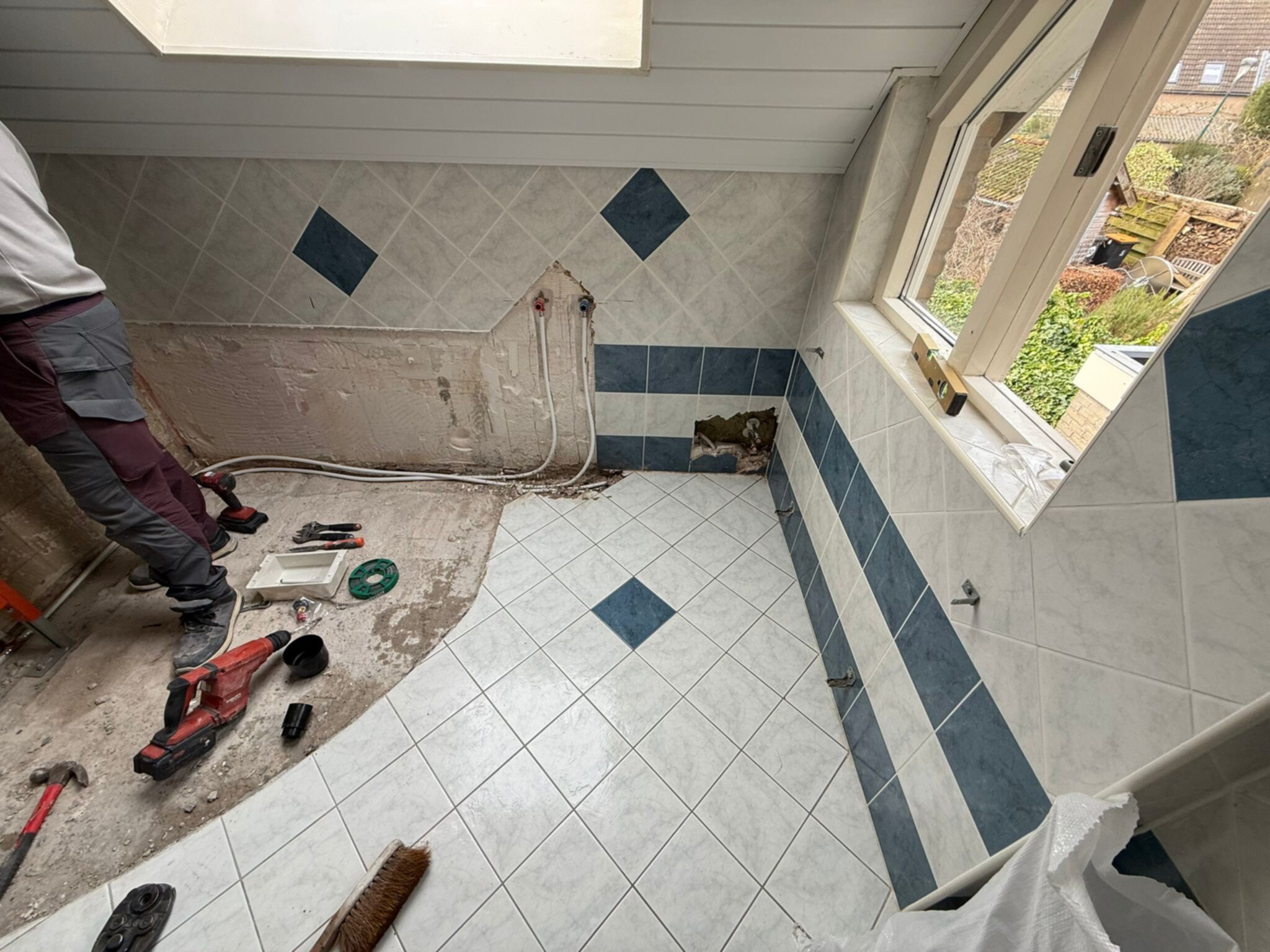 Sloop badkamer met gereedschap en man in werkkleding