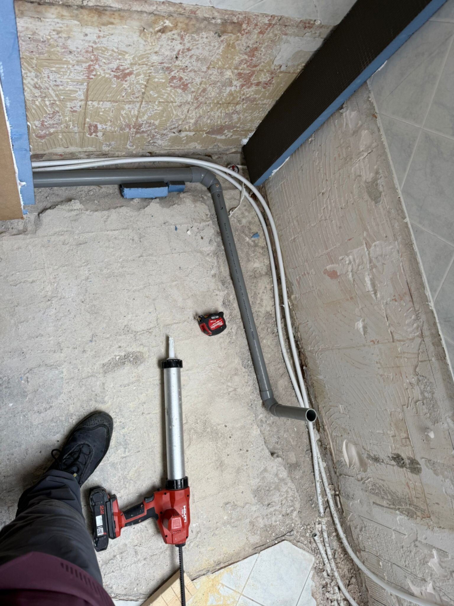 Sleuf in badkamer vloer met buizen en elektrische kabels