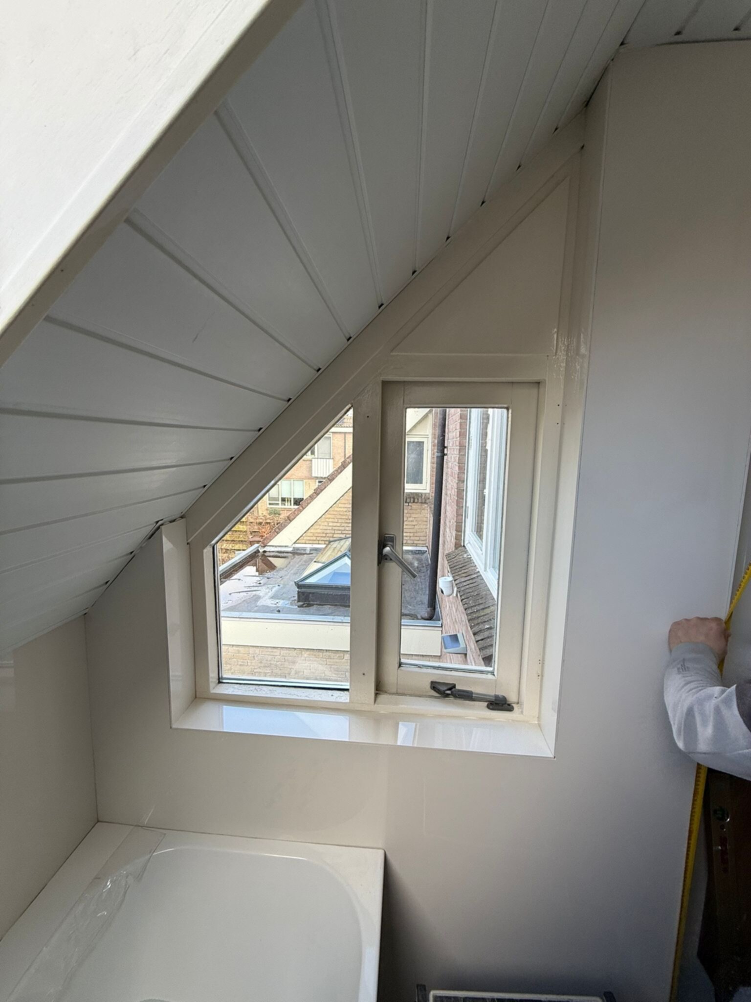 Schuin dakraam in badkamer met witte wand- en plafondpanelen