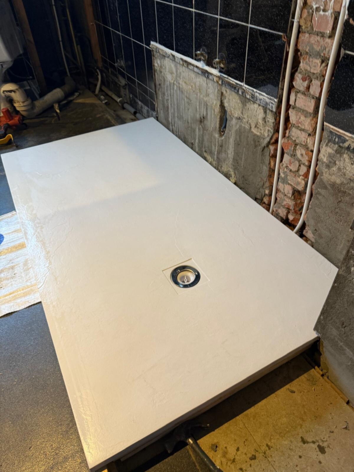Wit betegelde vloer met afvoerputje in badkamer tijdens renovatie