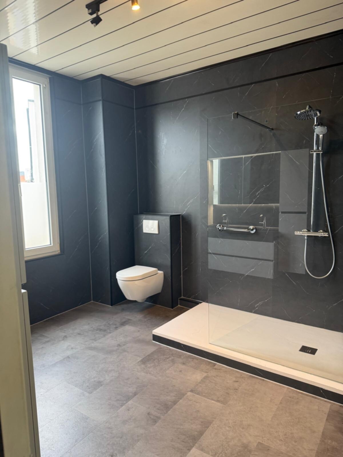 Moderne badkamer met grijze marmeren wanden en witte douchebak