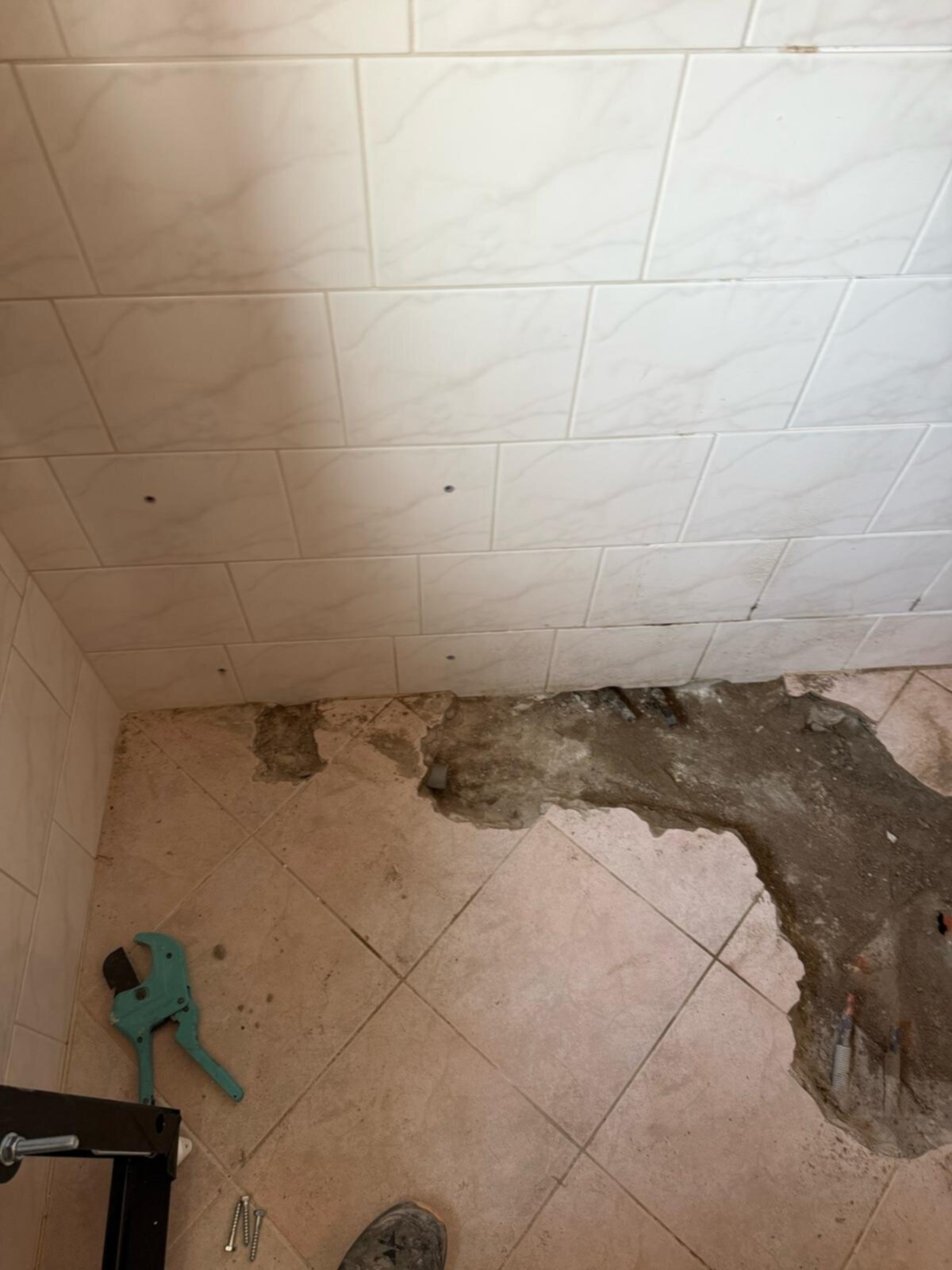 Slechte badkamer vloer met kapotte en losse tegels en gereedschap