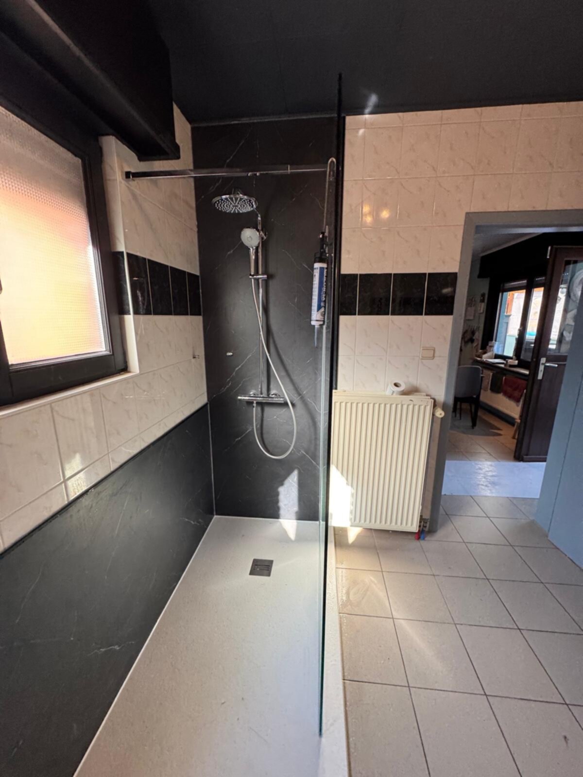 Douchecabine met zwarte en witte marmeren tegels en een glazen deur