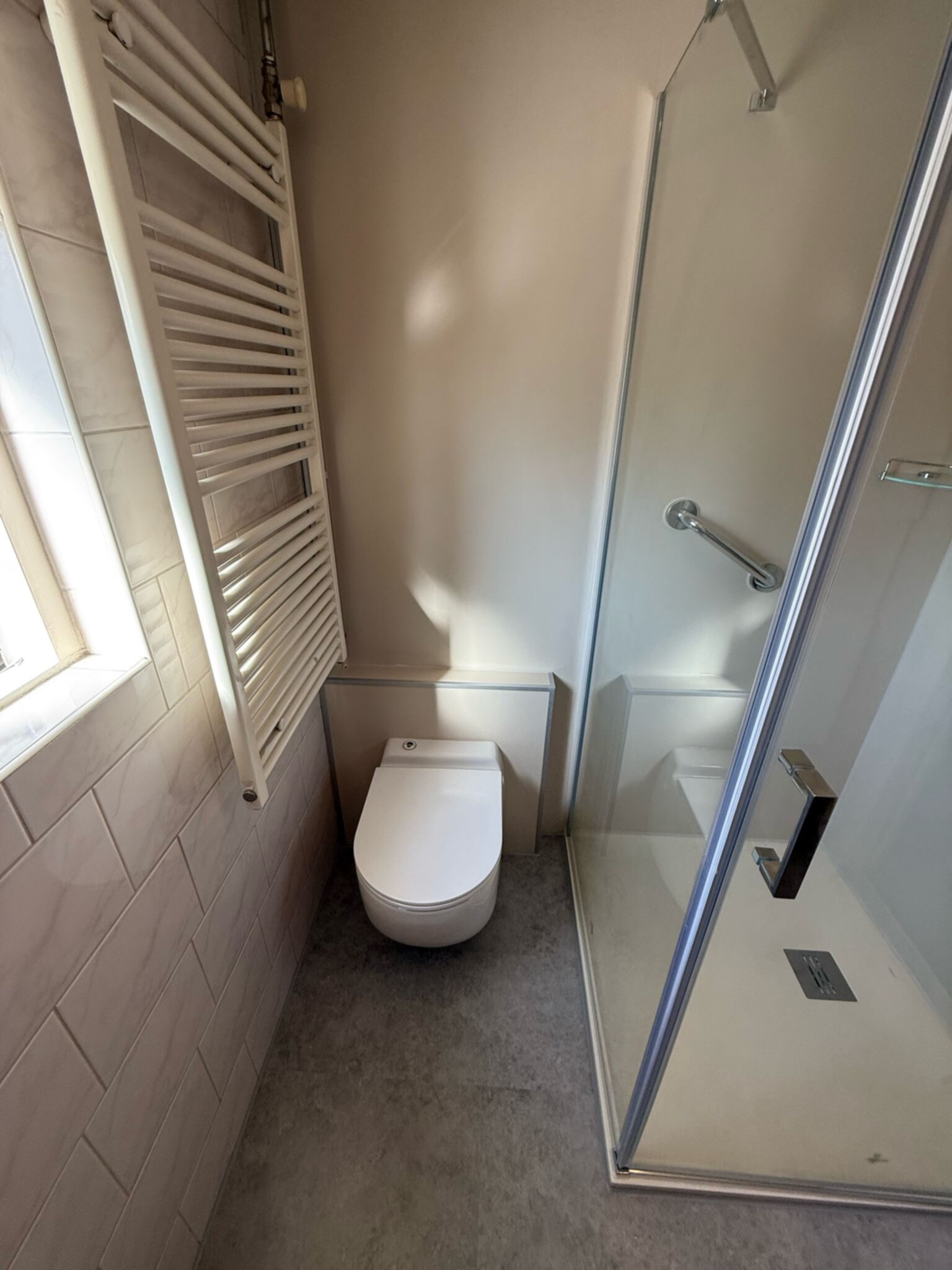 Moderne badkamer met witte toilet, glazen douchecabine en betegelde wanden