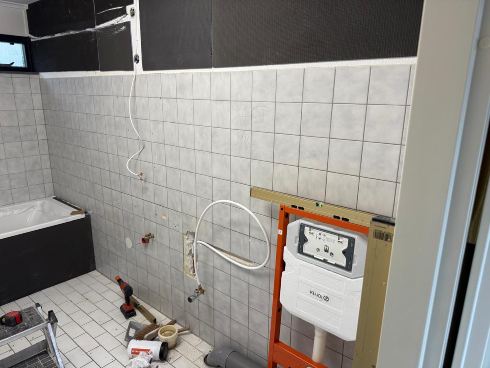 Badkamer renovatie in uitvoering met tegelwanden en -vloer, gereedschap en materialen