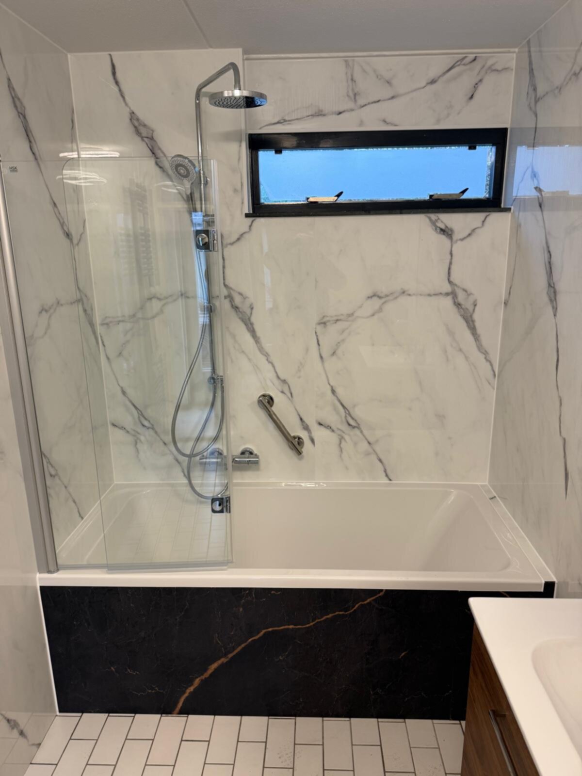 Badkamer met marmerlook tegels en een glazen douchecabine
