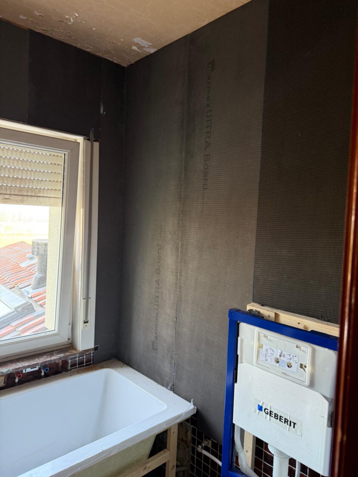 Badkamer in renovatie, grijs geschilderde muren en een witte badkuip