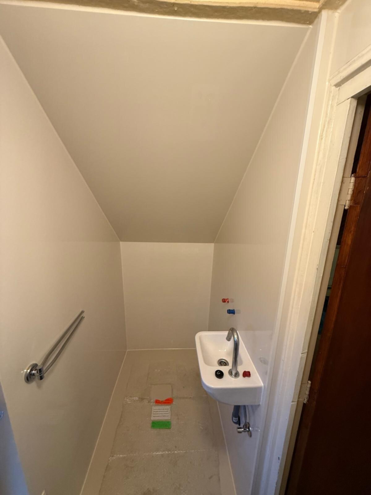 Kleine badkamer met witte wastafel en betegelde vloer in renovatie fase