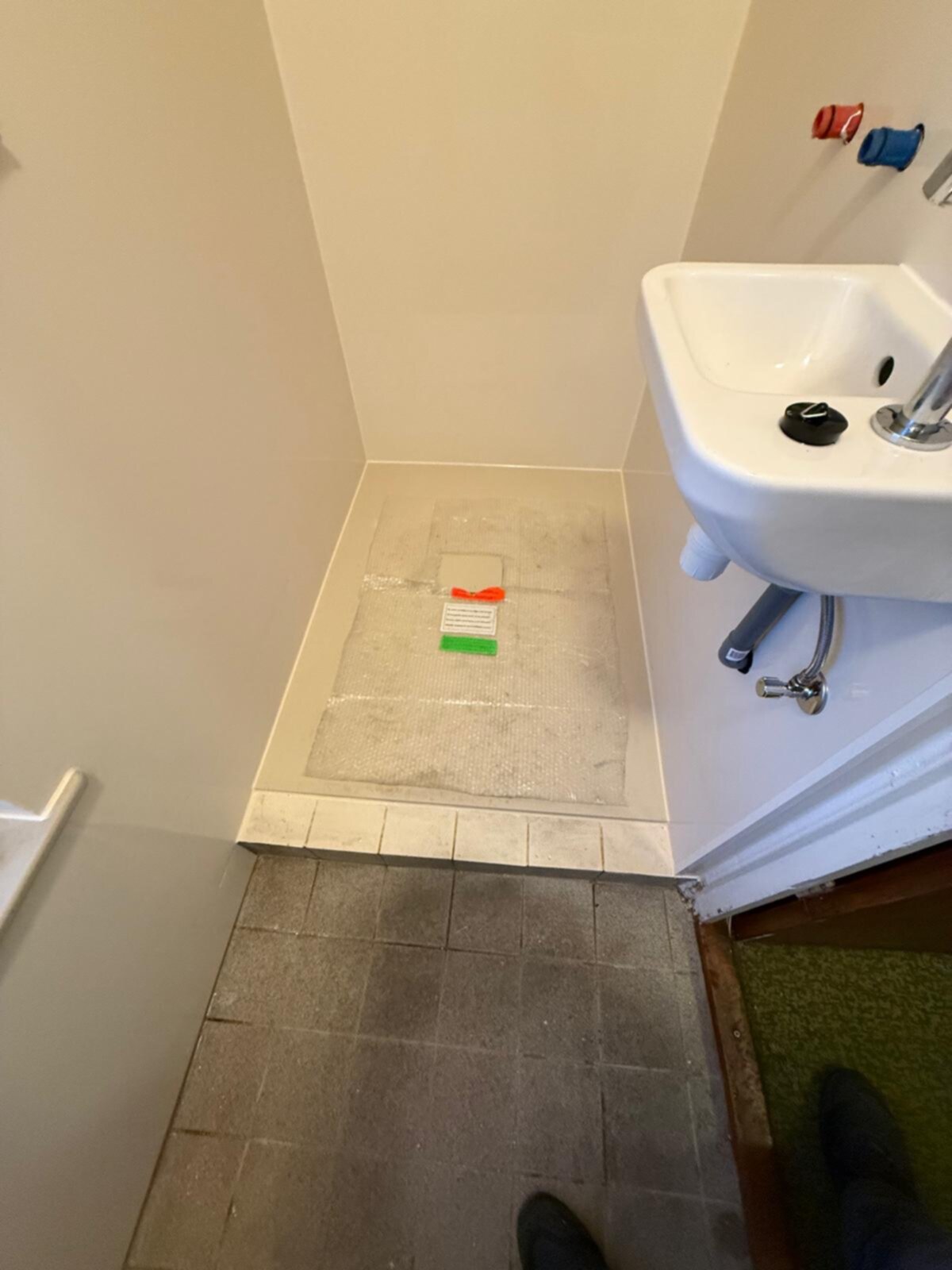 Badkamer tijdens renovatie met betegelde vloer en witte wastafel