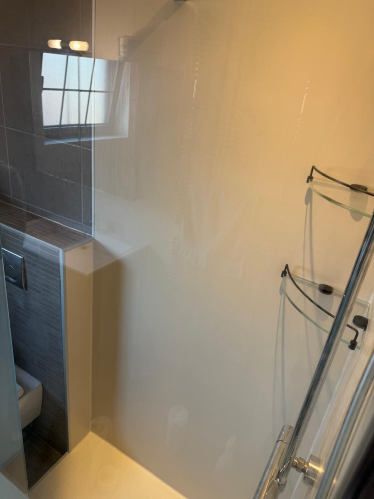 Douchecabine met glazen wand en deur, witte en grijze tegelwanden