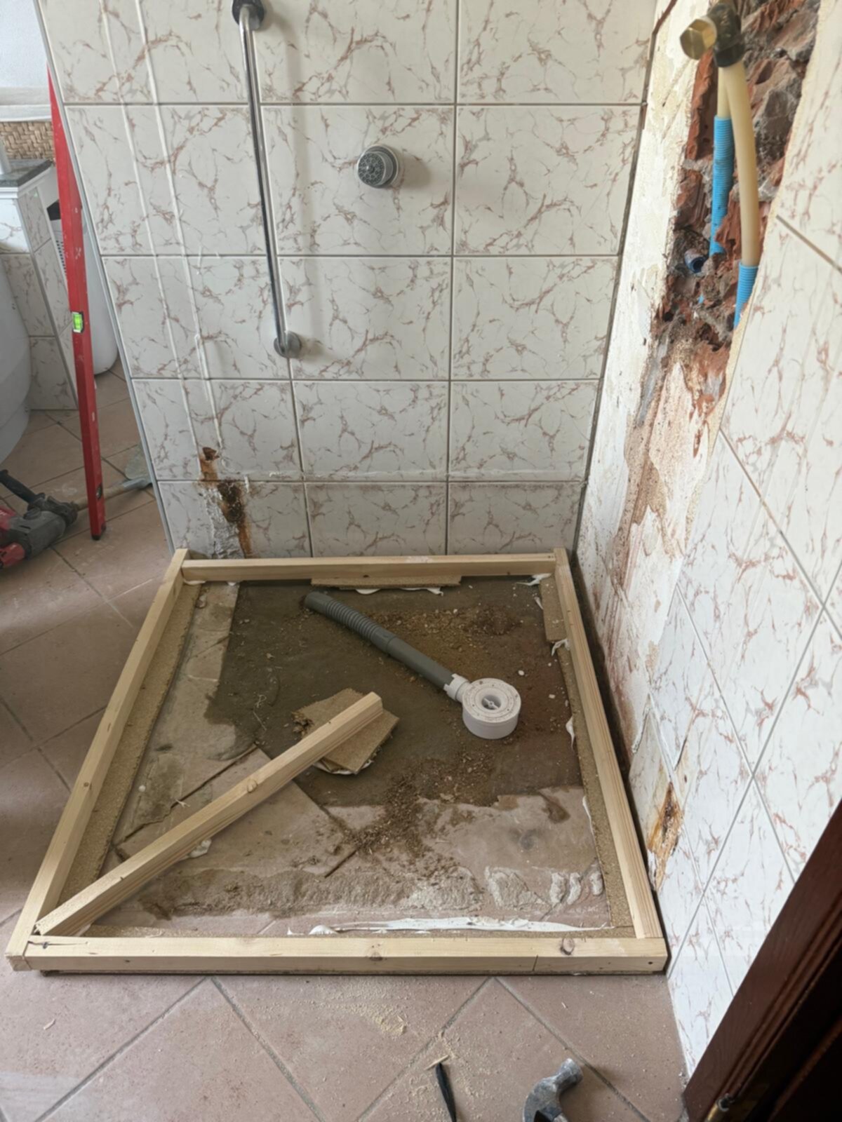 Badkamer renovatie, betegelde muren en vloer, houten frame voor nieuwe douche
