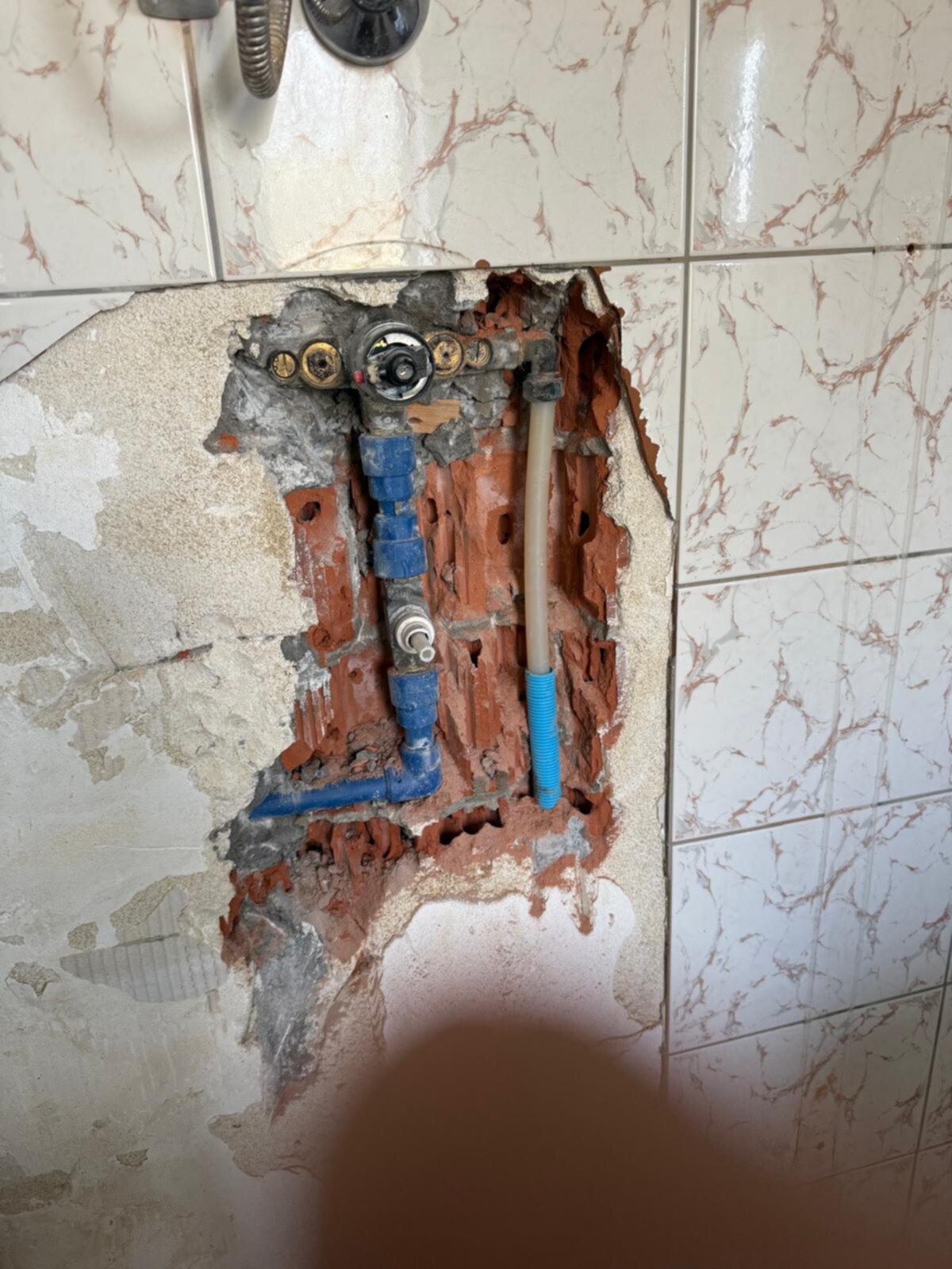 Slechte staat badkamer met kapotte tegel en openliggende leidingen