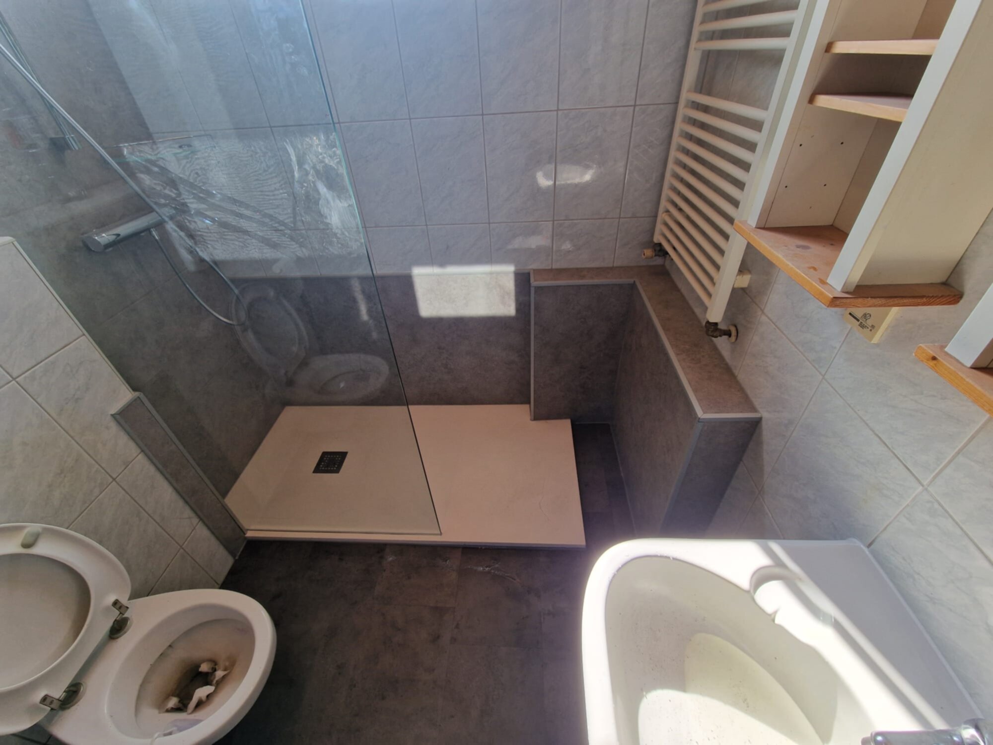 Badkamer met betegelde muren en vloer, toilet, douche en wastafel