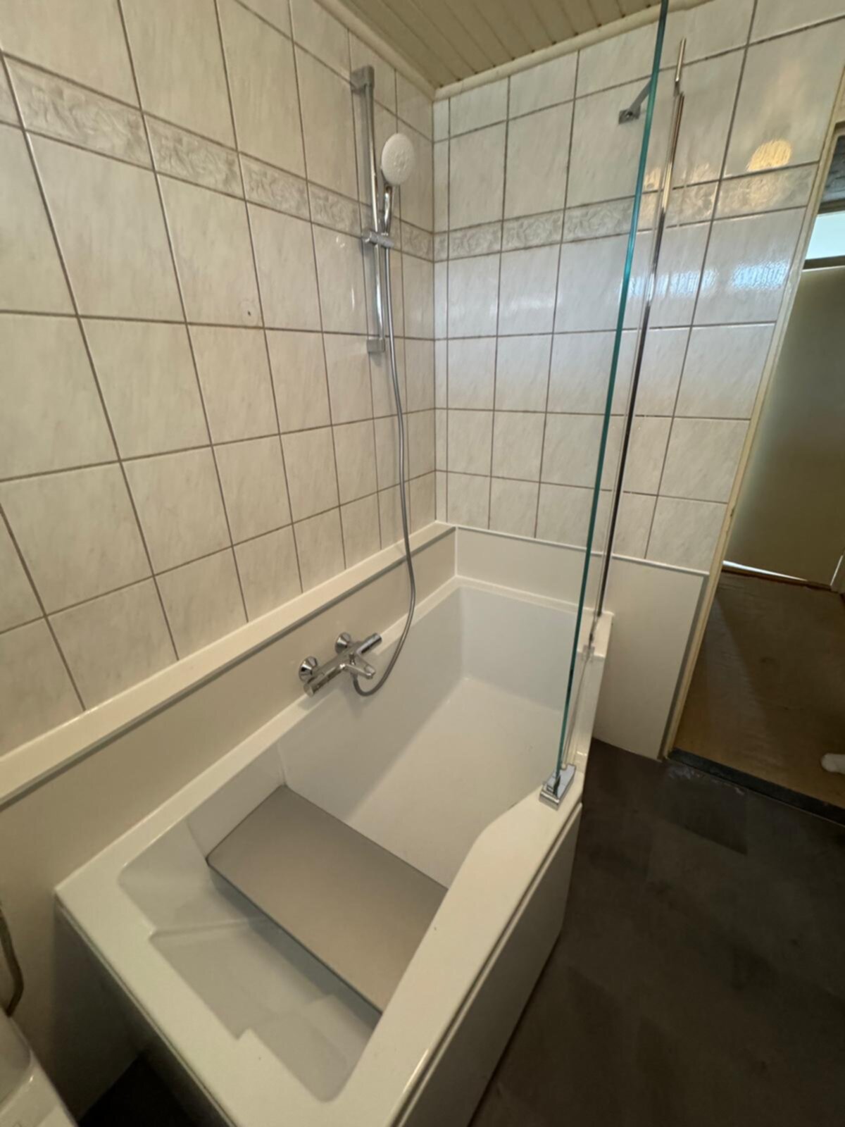 Wit bad met douche en betegelde wanden in een klassieke badkamer