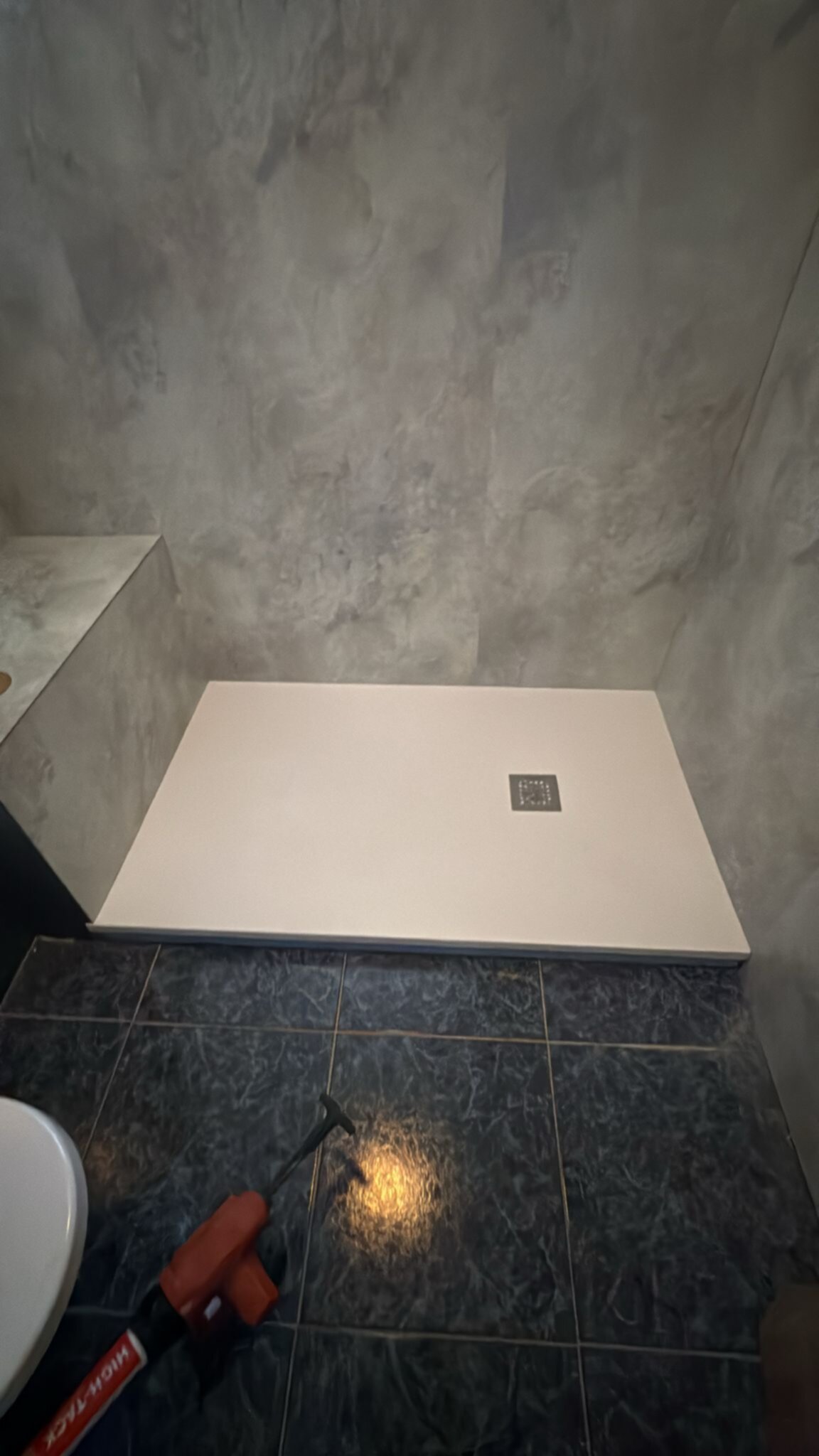 Douchebasis in moderne badkamer met grijze wanden en zwarte vloer