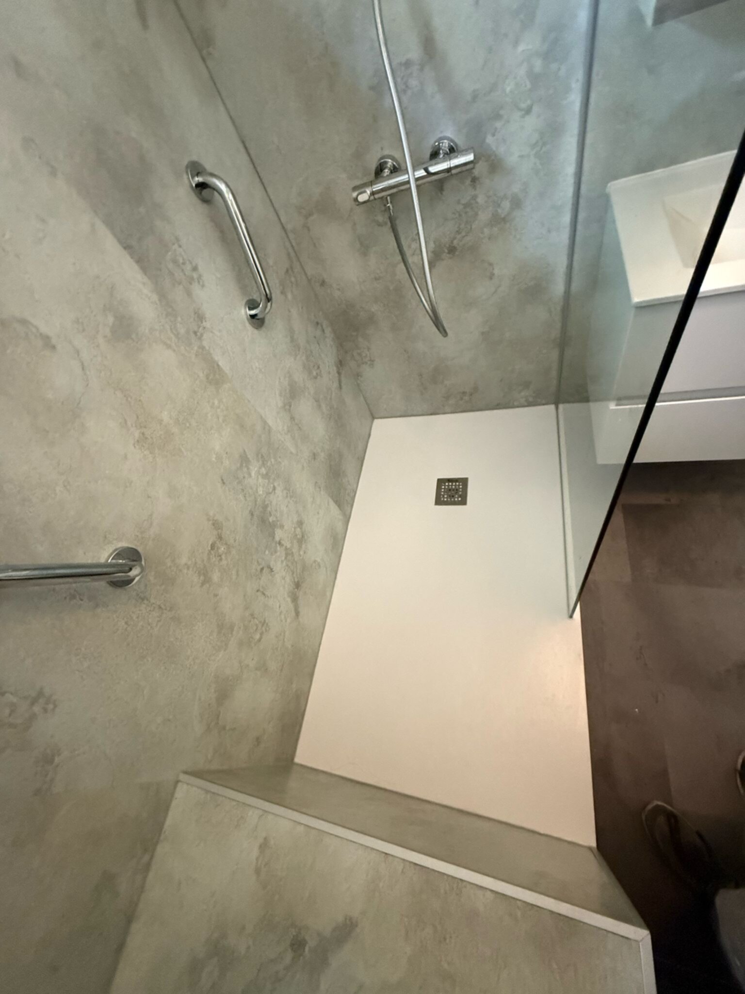 Douche area met grijs betegelde wanden en witte douchebak