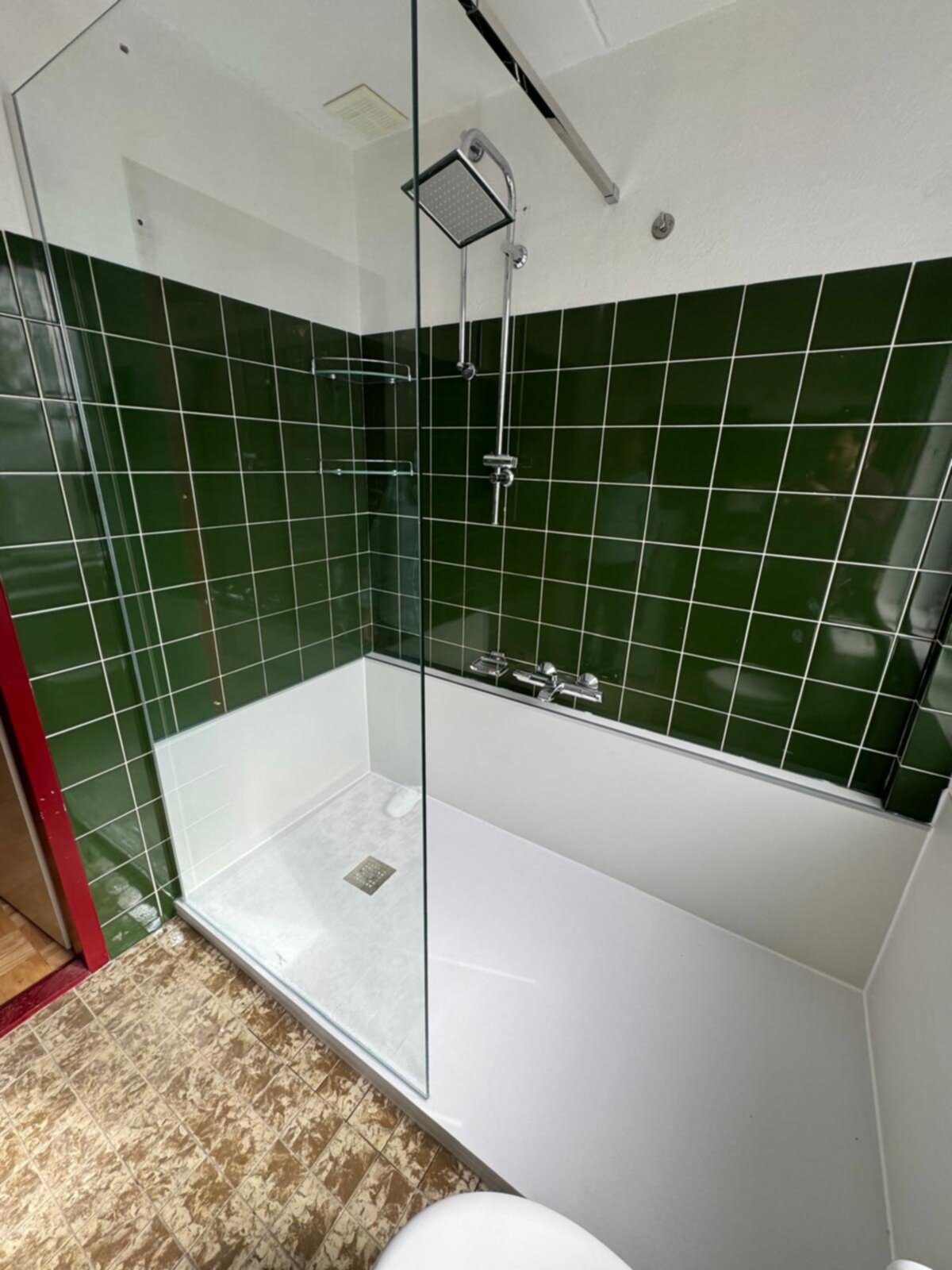 Douchecabine met groene tegels en glazen deur in moderne badkamer