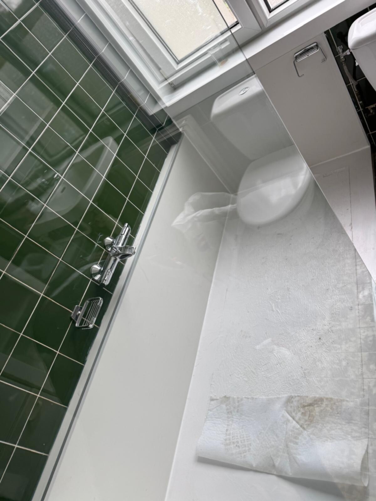 Badkamer met groene tegelwand en witte douchecabine tijdens renovatie
