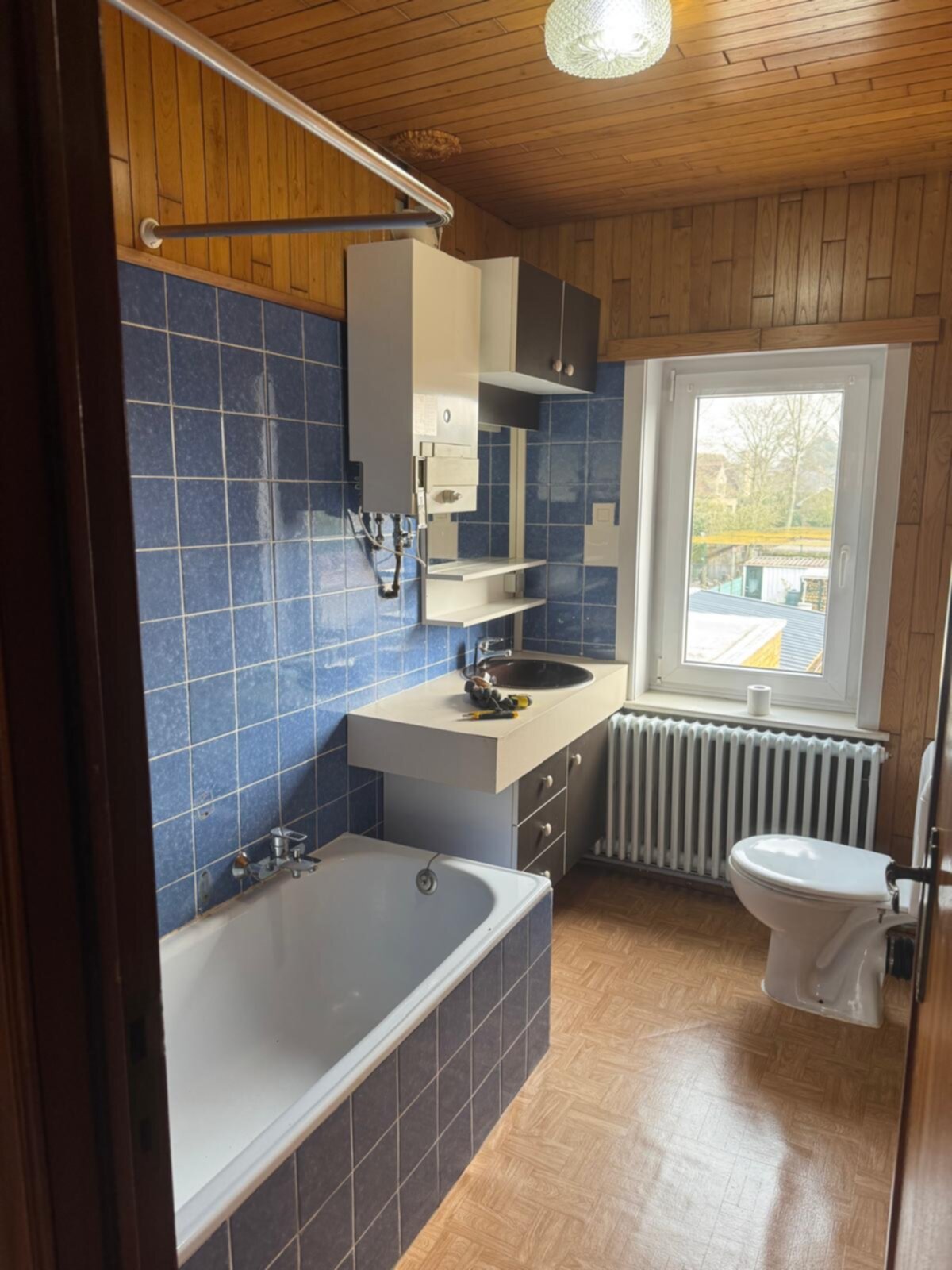 Badkamer met blauwe tegels, badkuip, wastafel en toilet