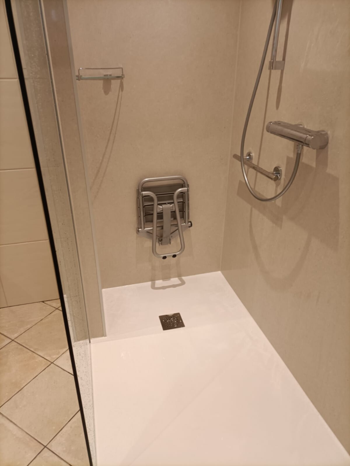 Douchecabine met beige tegels en witte douchebak