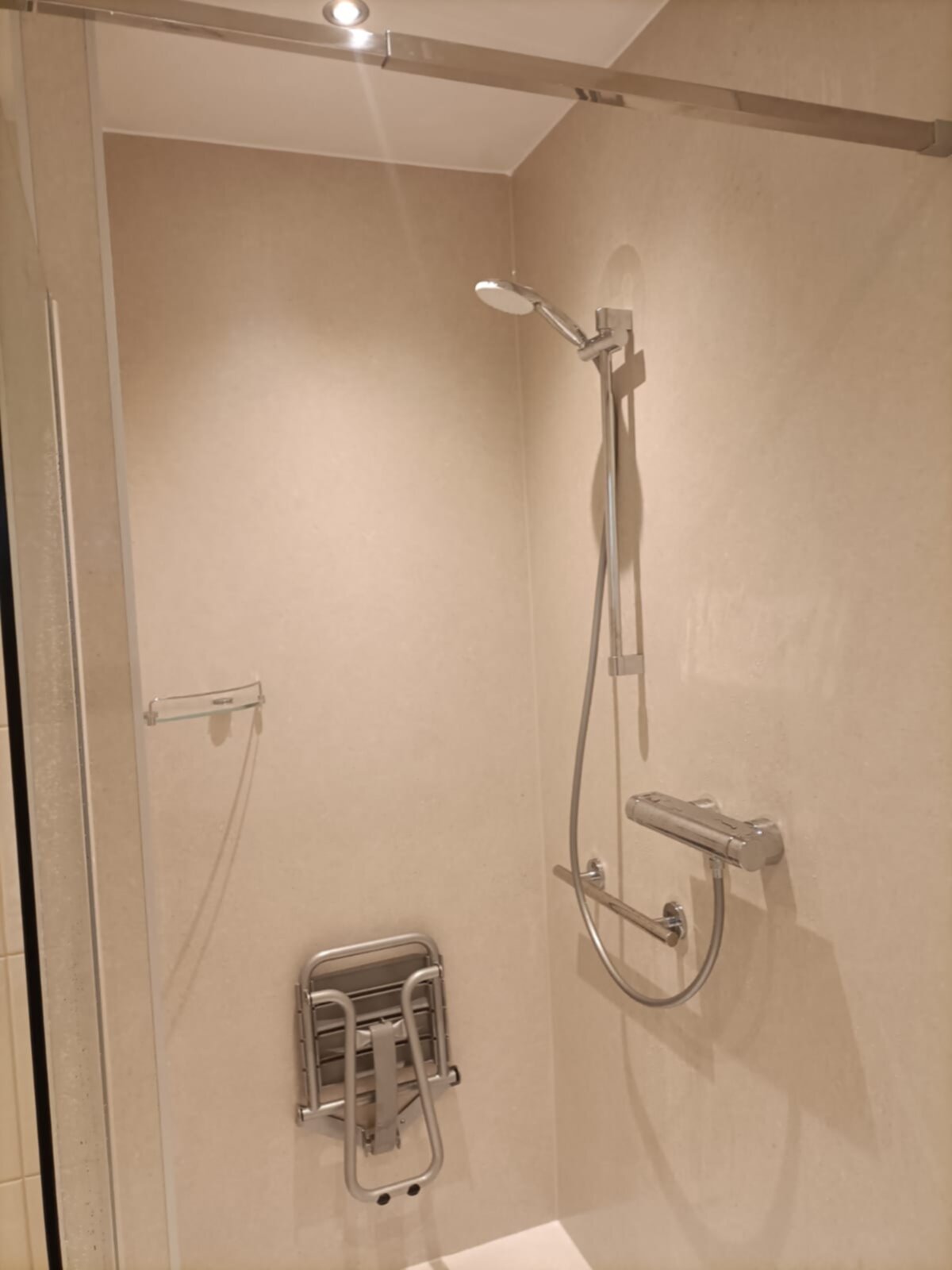 Douche met beige wanden, glazen deur en moderne metalen douchekraan en -set