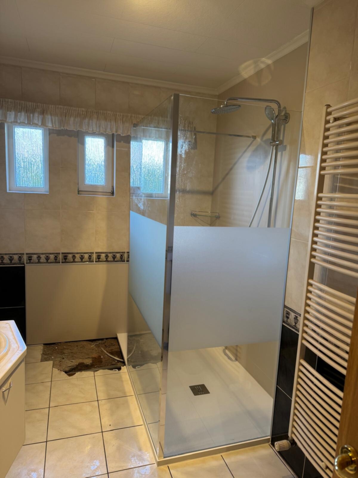 Badkamer met glazen douchecabine en beige betegeling