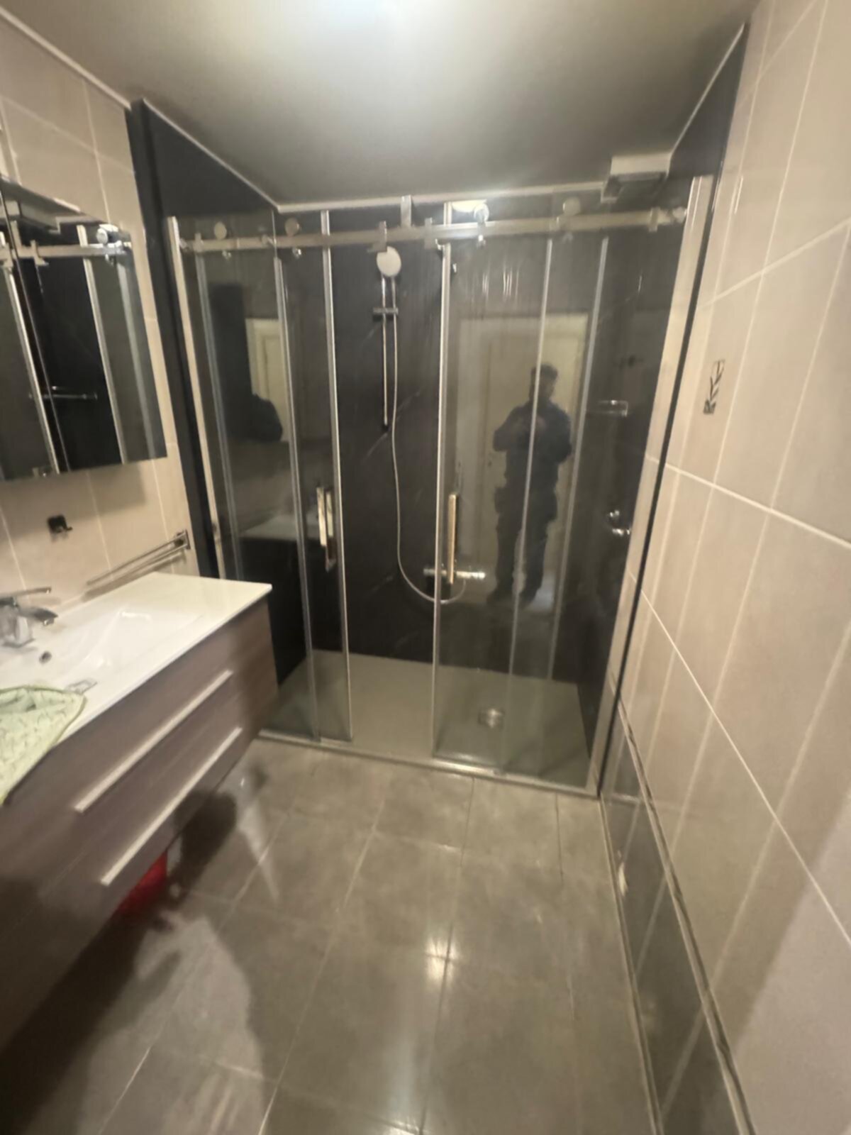 Moderne badkamer met glazen douchecabine en grijze tegels