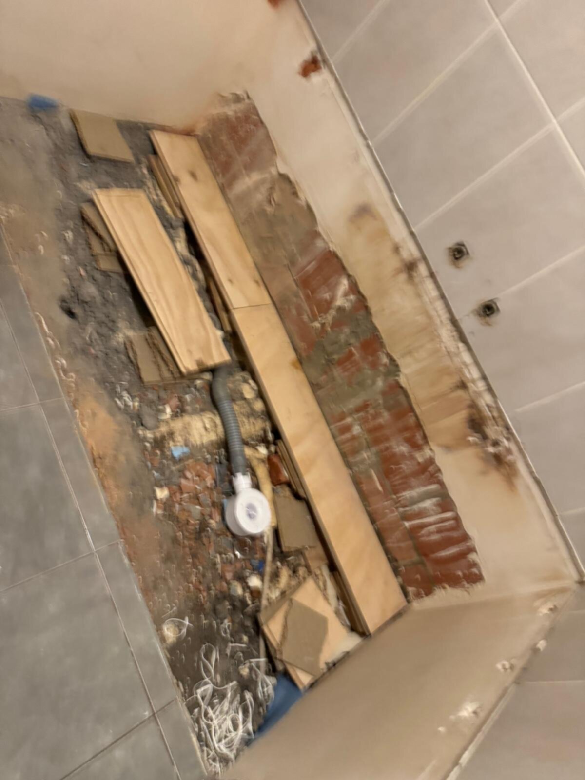 Sloopwerk badkamer, hout en puin op de grond, blootgestelde bakstenen muur